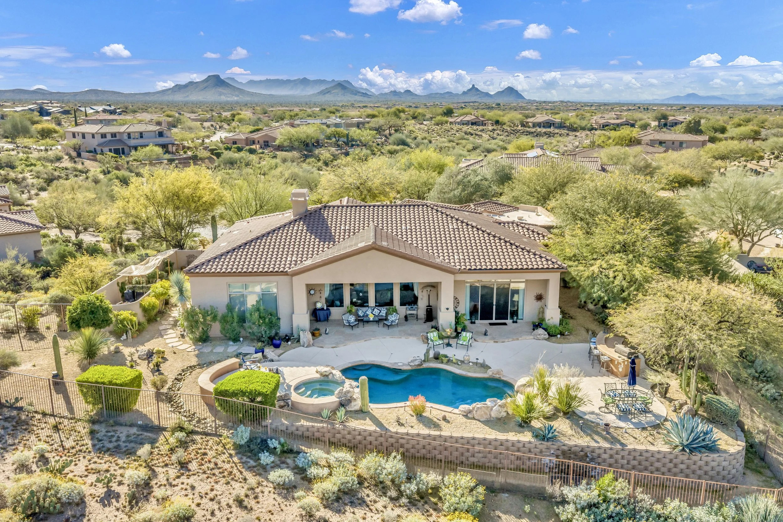 This aerial real estate photography showcases a beautiful Scottsdale, AZ home with a backyard pool, surrounded by desert landscaping and mountain views, perfect for outdoor living and relaxation.