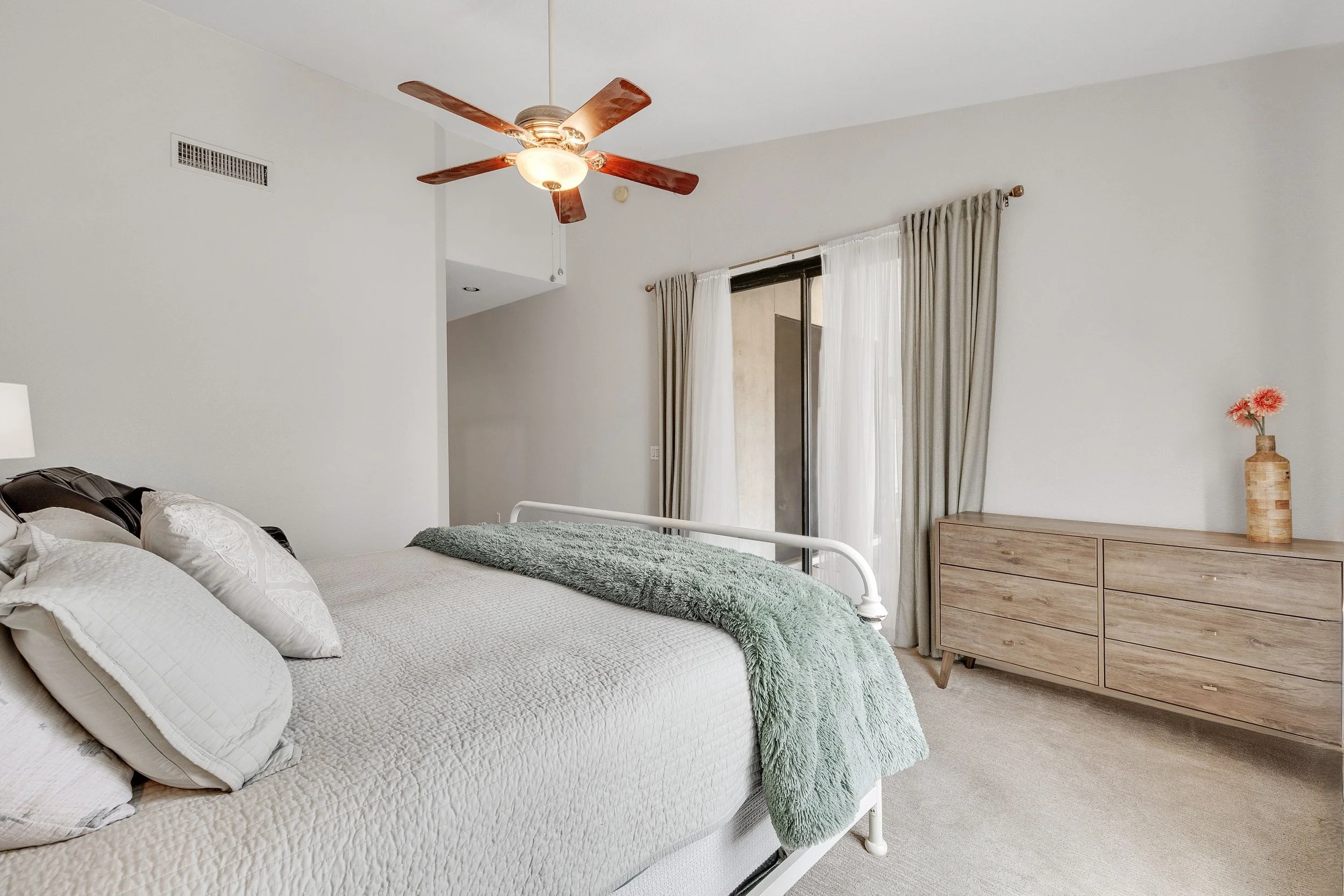 This bedroom interior in Goodyear, AZ features natural light, a comfortable bed, and modern furniture, captured with professional real estate photography to enhance the home's appeal.