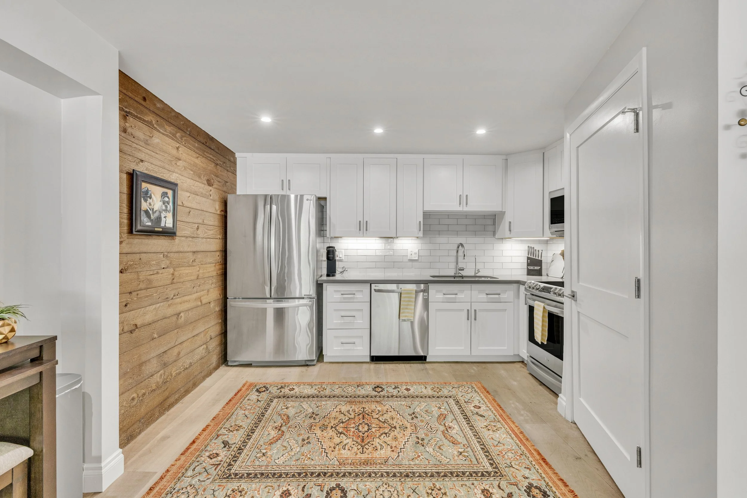 This bright modern kitchen in Paradise Valley, AZ features stainless steel appliances, white cabinetry, and a warm wood accent wall, captured with professional real estate photography.