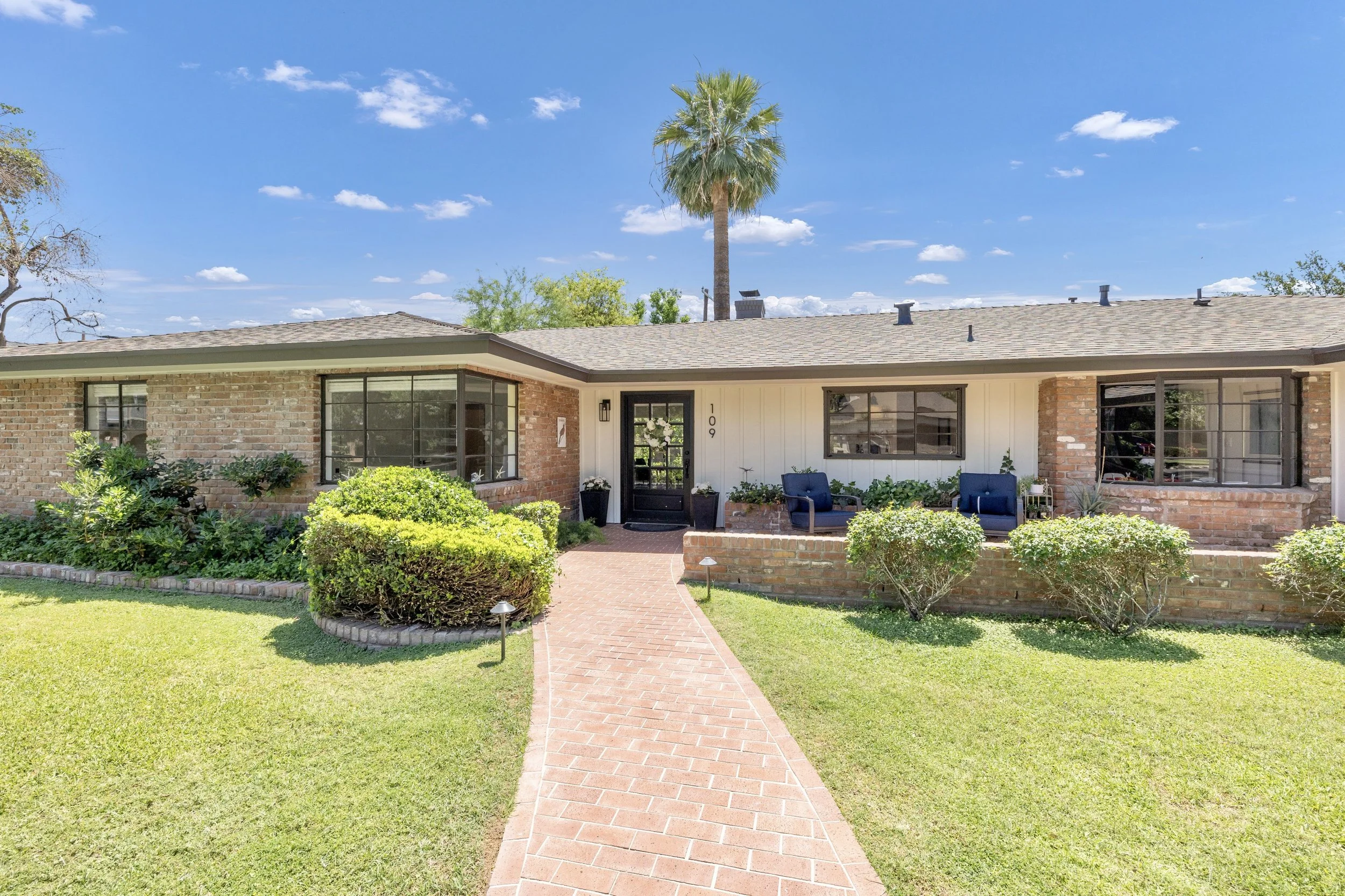 This charming brick ranch home in Phoenix, AZ features a well-maintained lawn and inviting front porch, captured beautifully with professional real estate photography.