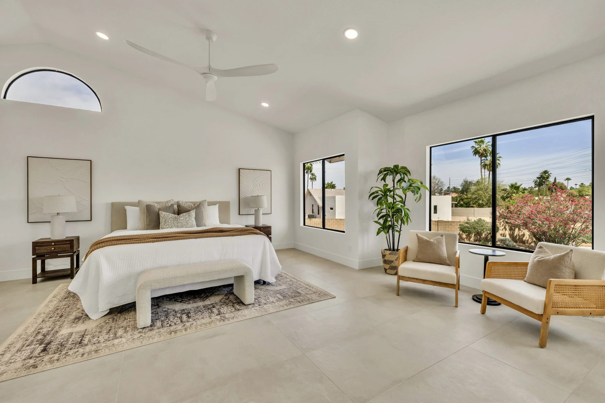 This bright bedroom features large windows and a cozy seating area, perfectly captured in real estate photography in Scottsdale, AZ.