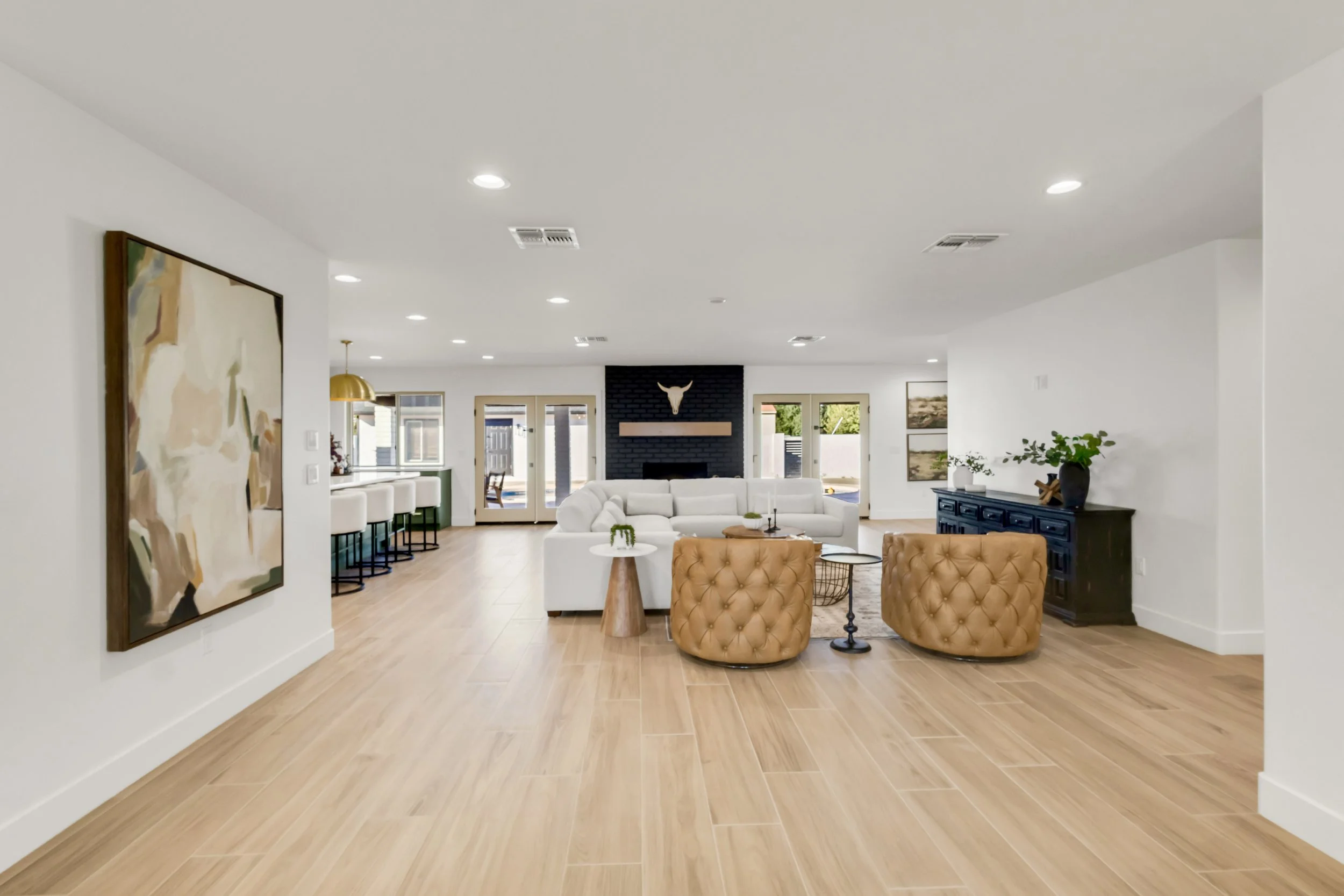 Bright living room in Phoenix, AZ with open layout, modern furnishings, and view of kitchen with gold pendant lighting.