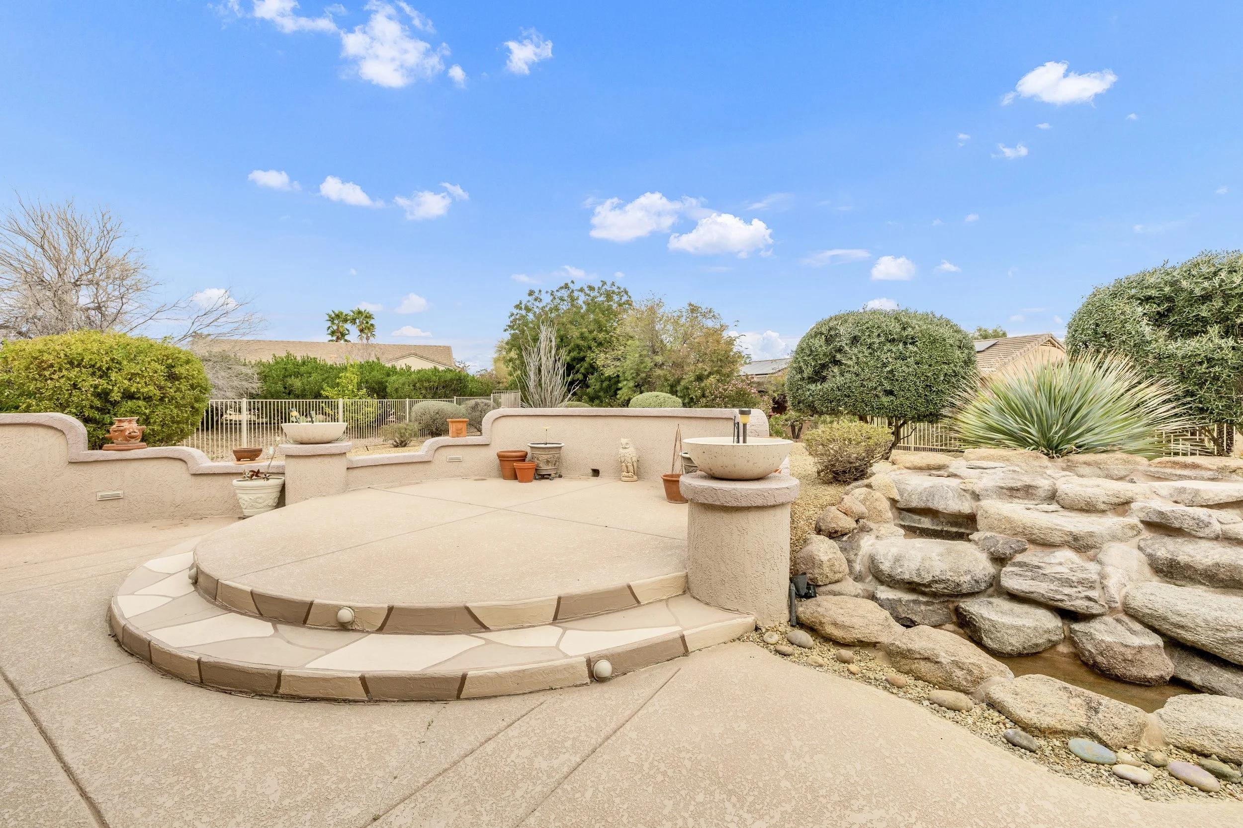 Enjoy this spacious backyard patio with a stepped platform and stone water feature, perfectly captured in real estate photography in Surprise, AZ.
