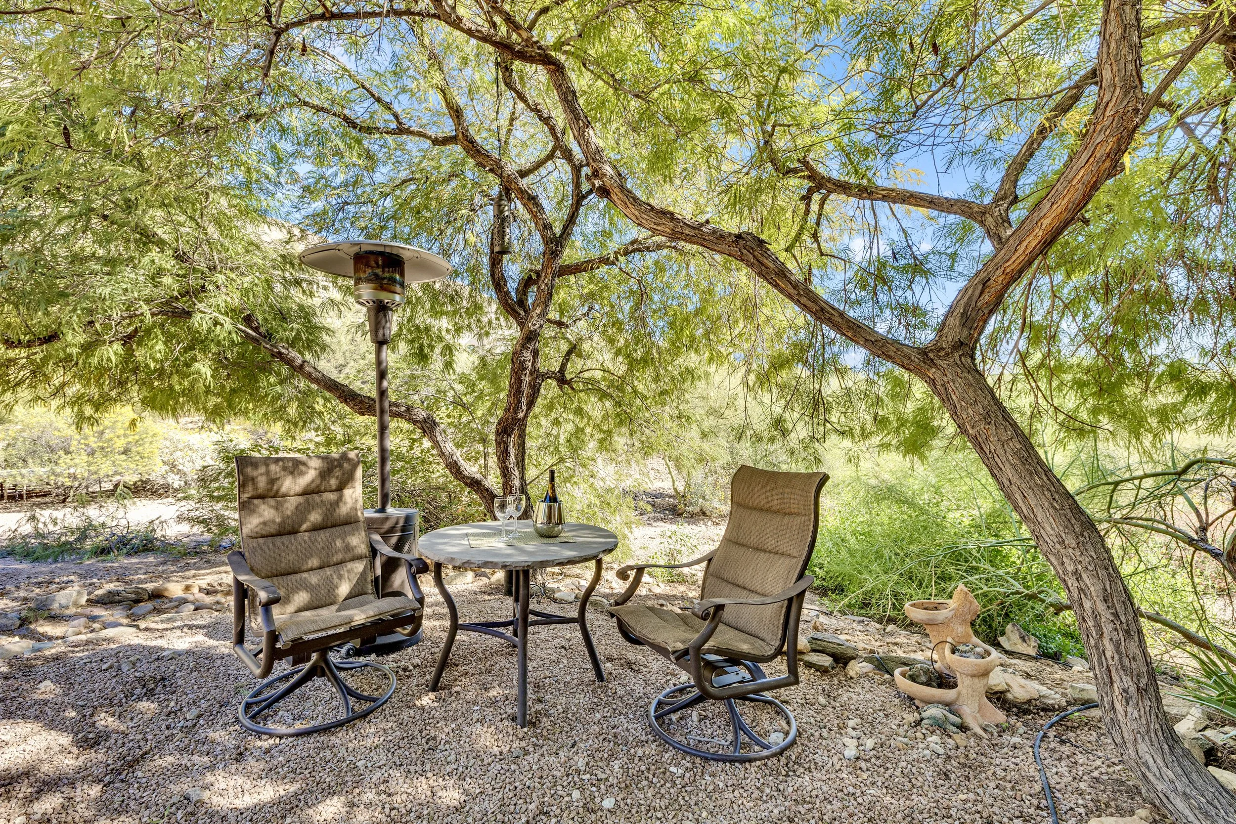This shaded outdoor patio in Paradise Valley, AZ features comfortable seating and a small table, captured with expert real estate photography to highlight the serene backyard space.
