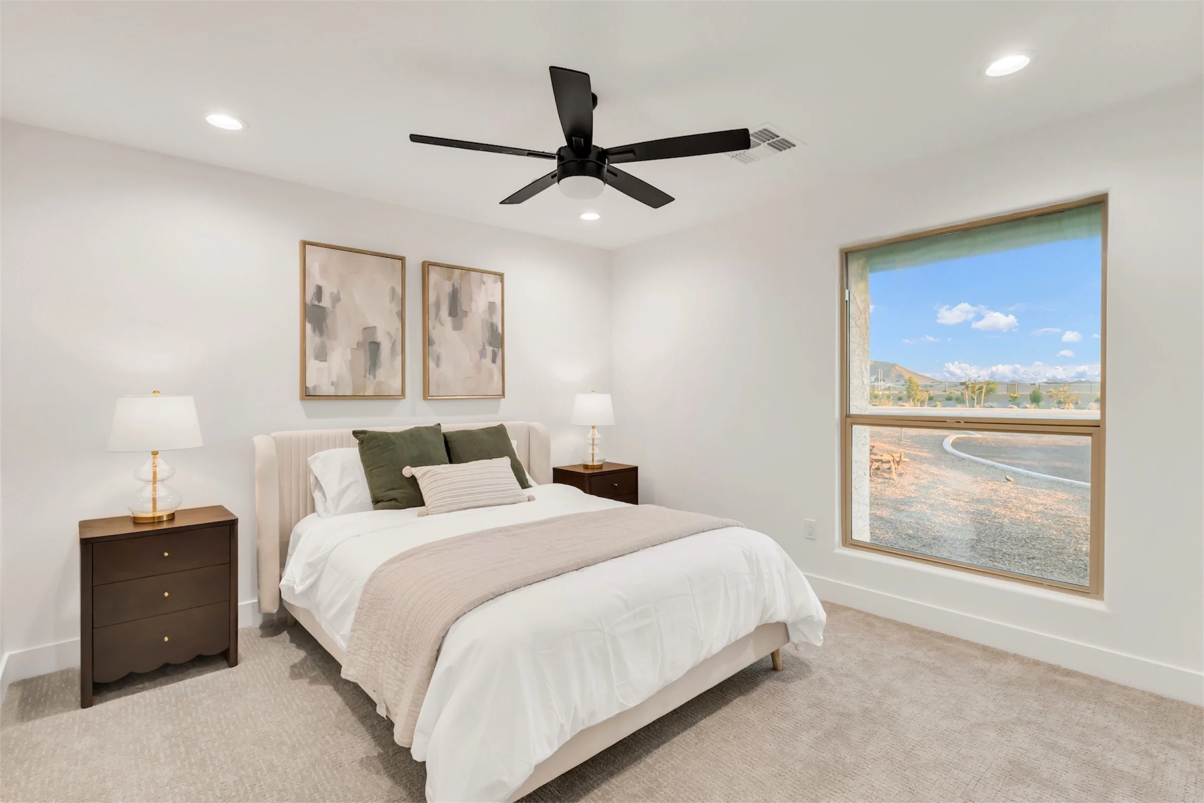 Cozy guest bedroom with neutral tones and large window featuring desert views in Phoenix, AZ.