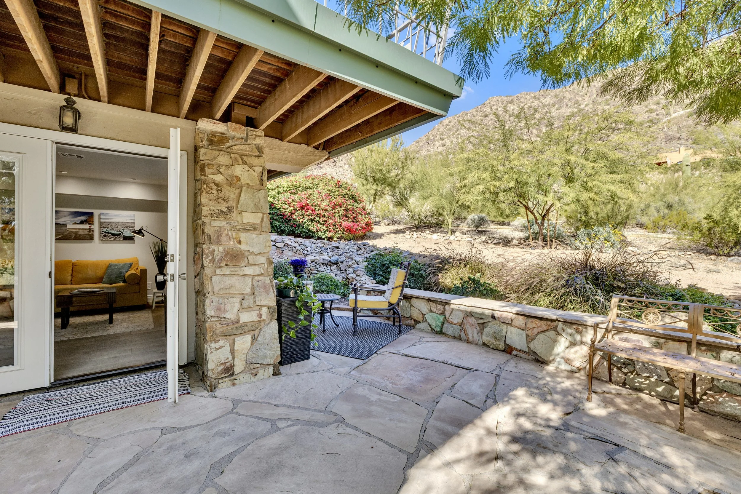 This stylish backyard patio with stone flooring and mountain views in Paradise Valley, AZ is perfectly captured in this vibrant real estate photography shot, highlighting outdoor living potential.