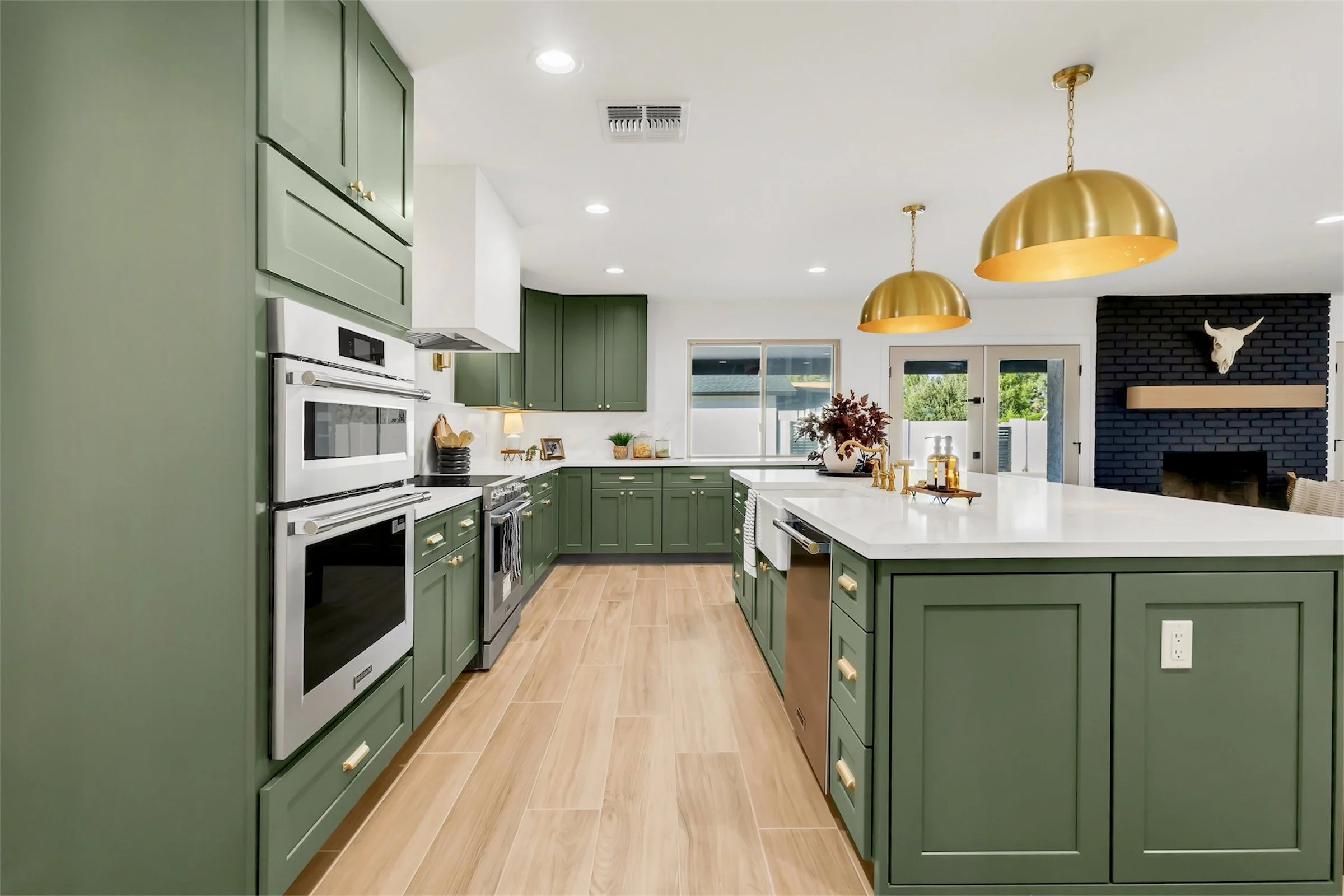 Spacious kitchen in Phoenix, AZ with green cabinetry, gold pendant lighting, and a large white quartz island.