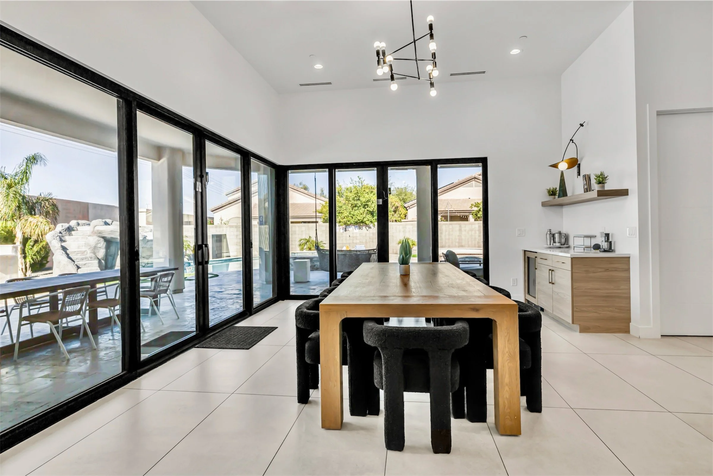 Bright dining room with panoramic sliding doors, modern chandelier, and views of the backyard and pool in Scottsdale, Arizona.