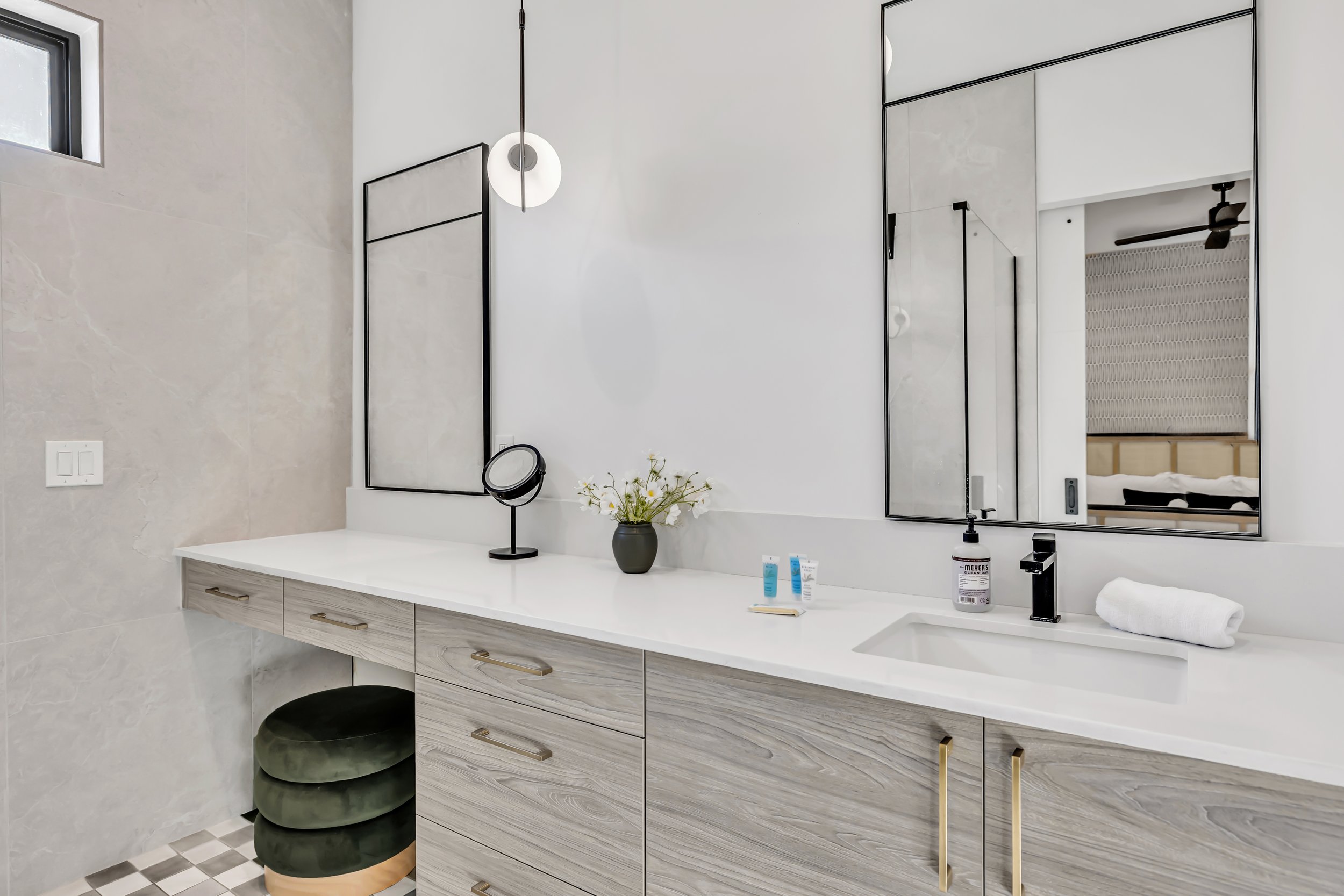 Modern bathroom vanity featuring dual mirrors, gold hardware, a white countertop, and soft decorative accents in Scottsdale, Arizona.