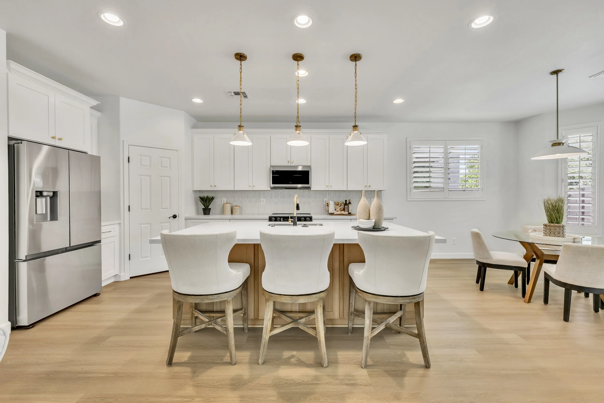 This modern kitchen with an island, stools, and adjacent dining area showcases real estate photography in Gilbert, AZ, highlighting homes in the Morrison Ranch neighborhood.