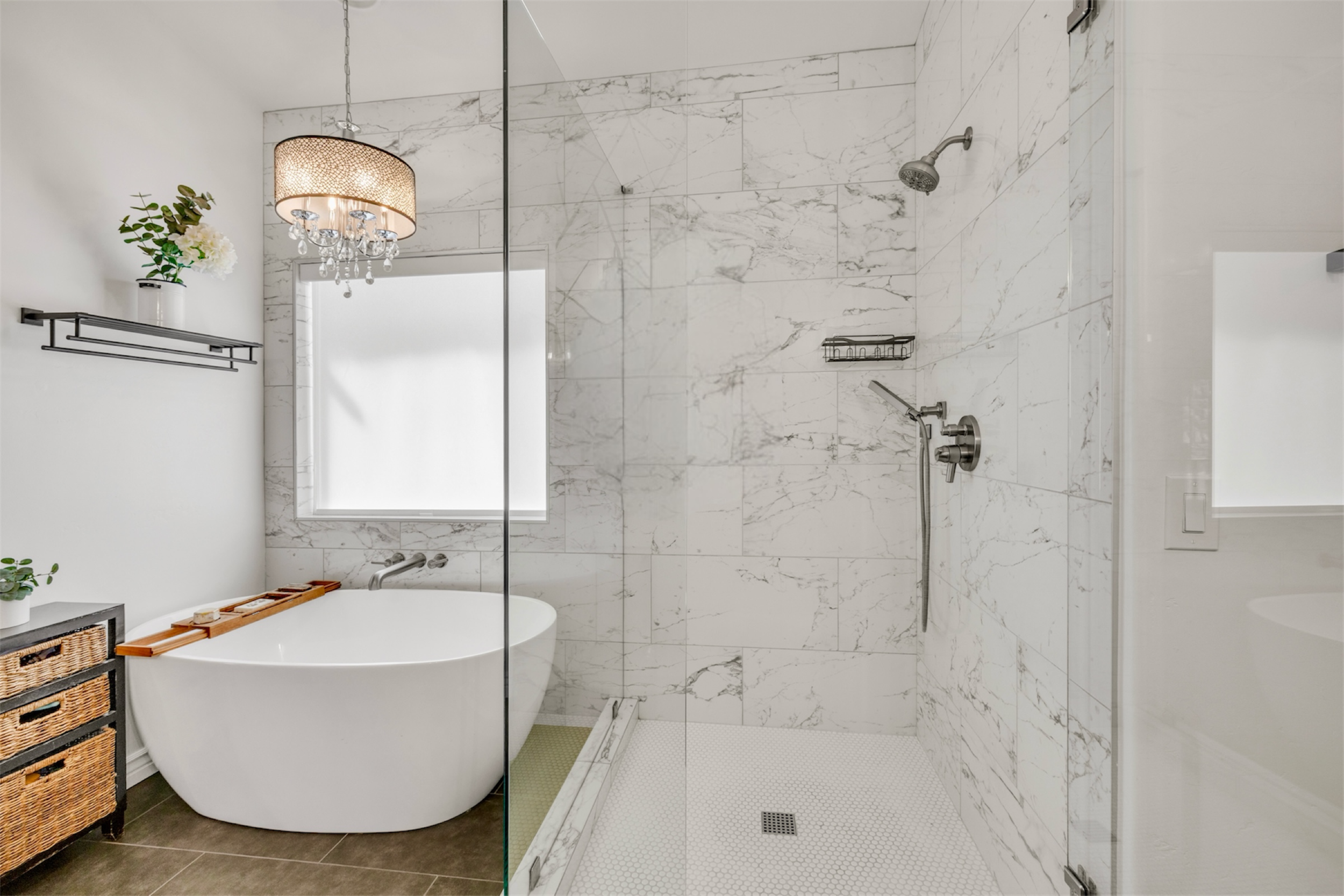 This modern bathroom in Gilbert, AZ, features elegant marble tile, a walk-in shower, and a freestanding tub, captured with professional real estate photography for a luxurious home appeal.