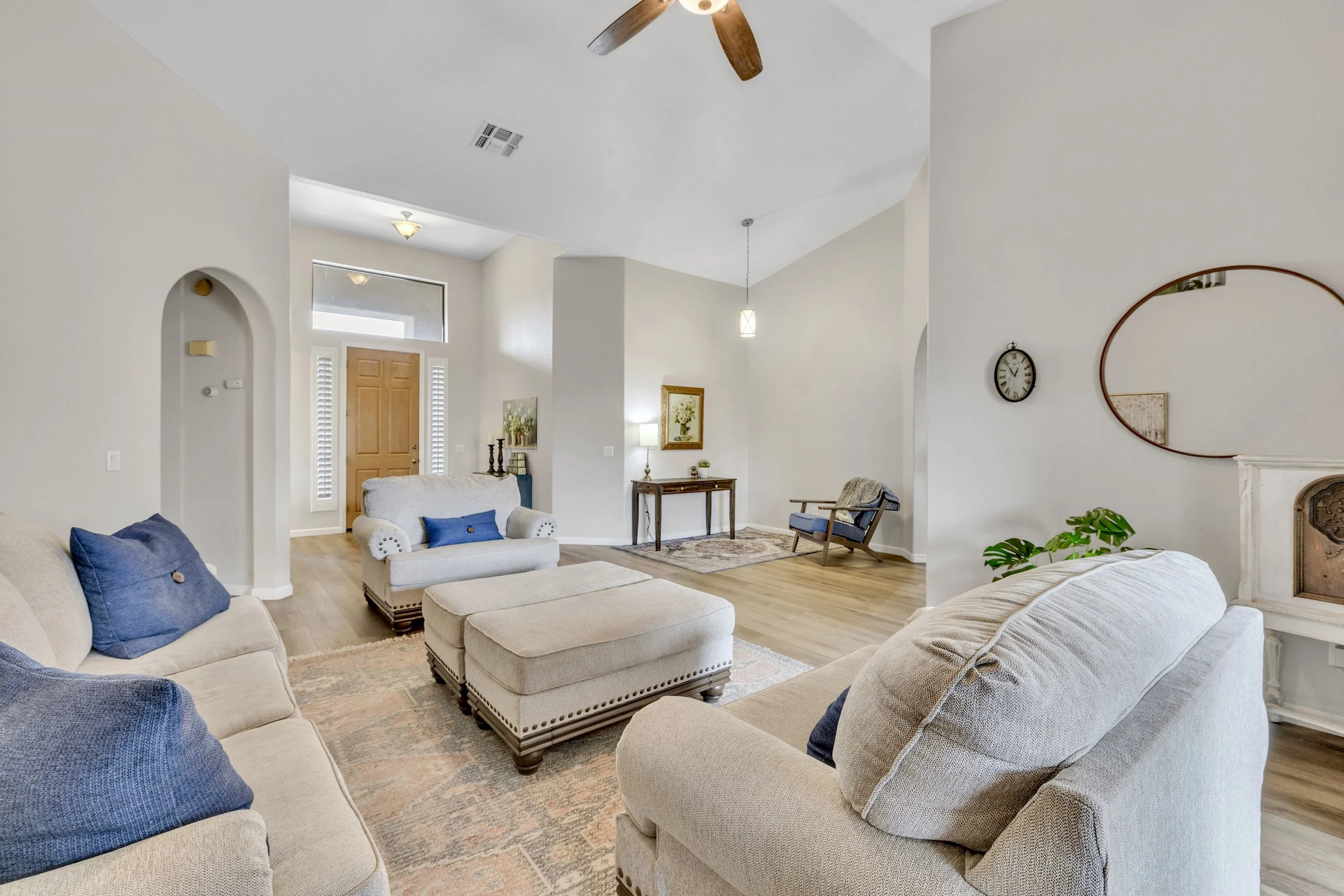 This bright living room in Goodyear, AZ features cozy couches with blue pillows and tasteful decor, captured with expert real estate photography to highlight the home's inviting interior.