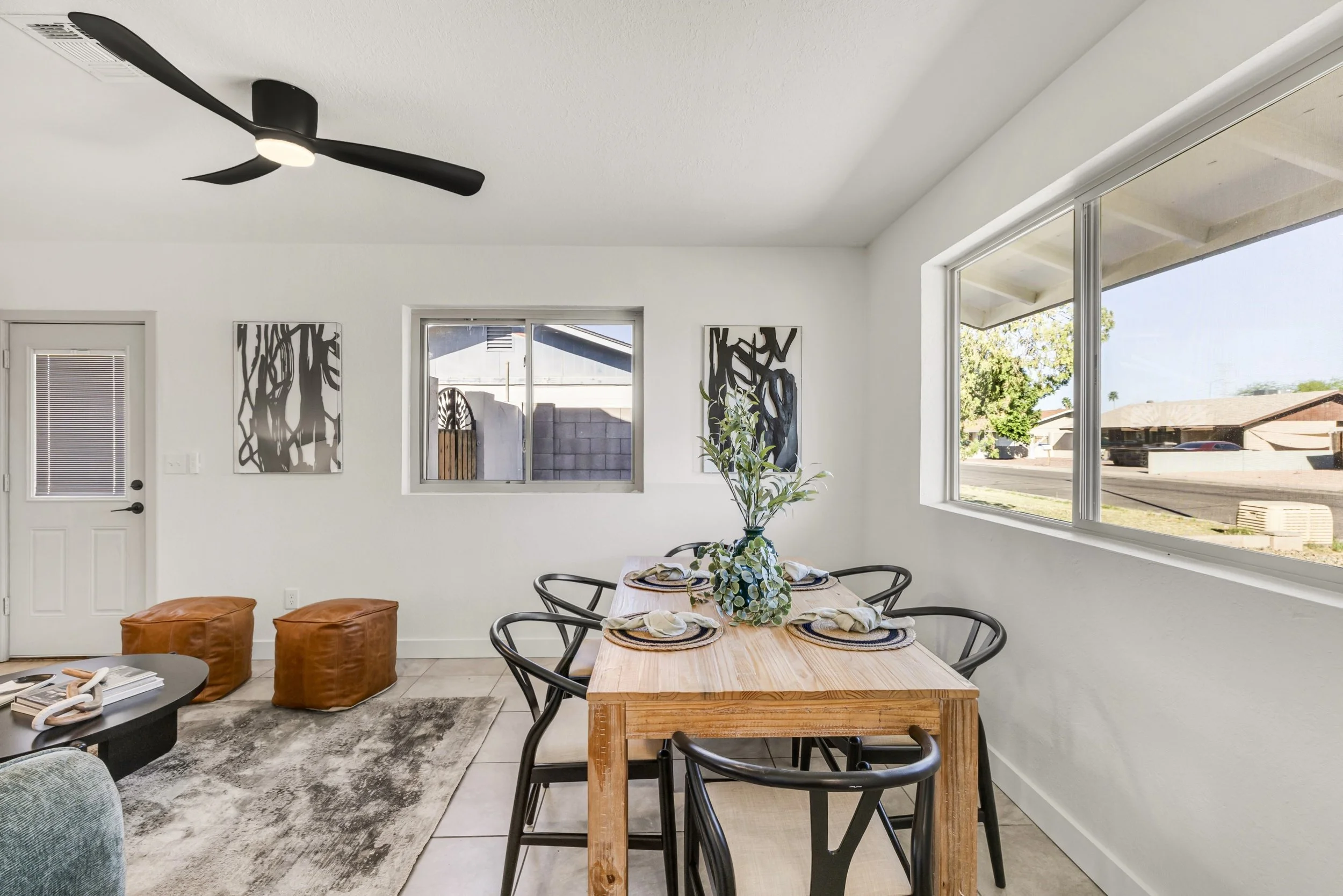 Bright dining area with large windows and black chairs in a home located in Mesa, AZ, highlighted through professional real estate photography.