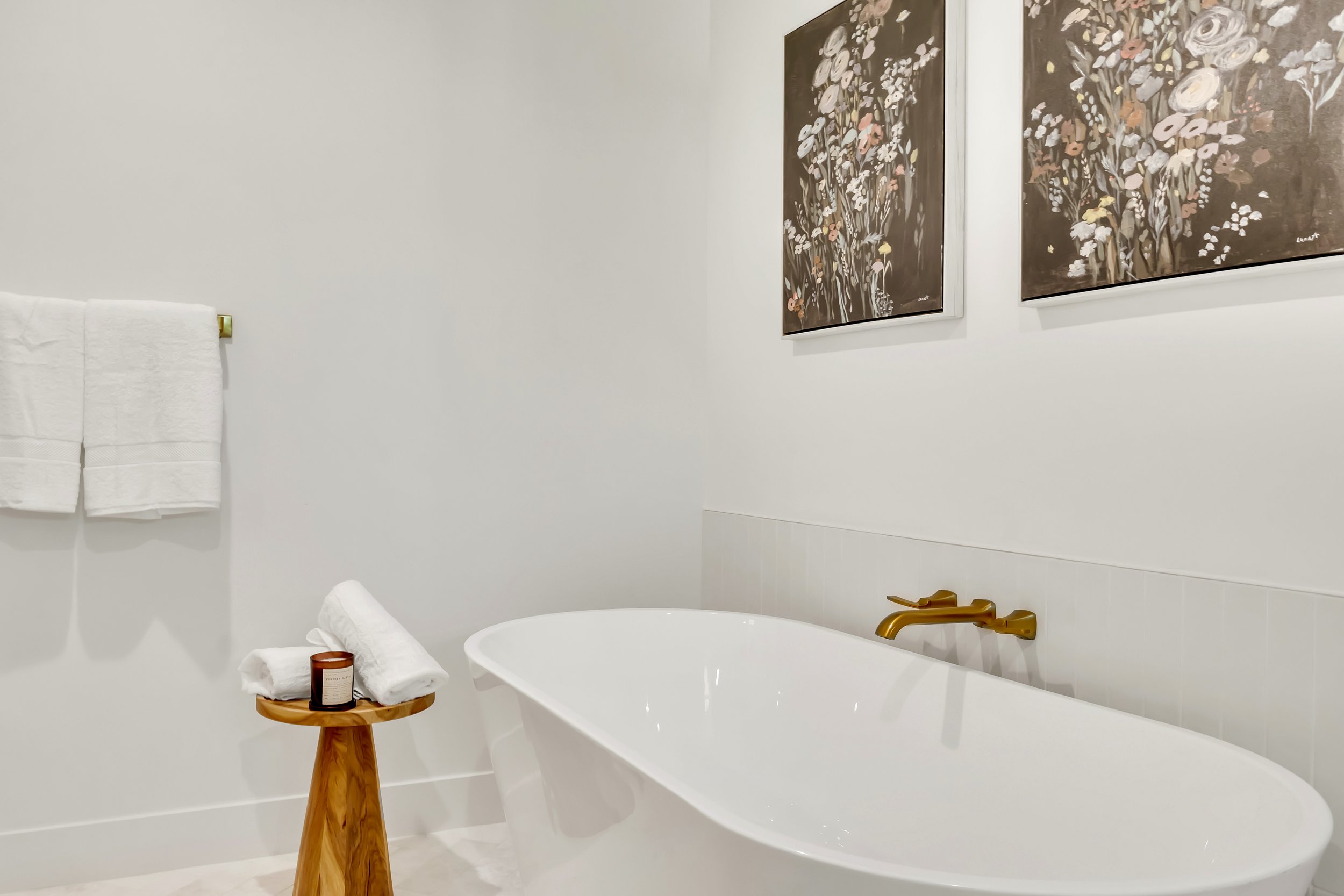 Serene bathroom in Phoenix, AZ with freestanding tub, floral wall art, and minimalist gold fixtures.