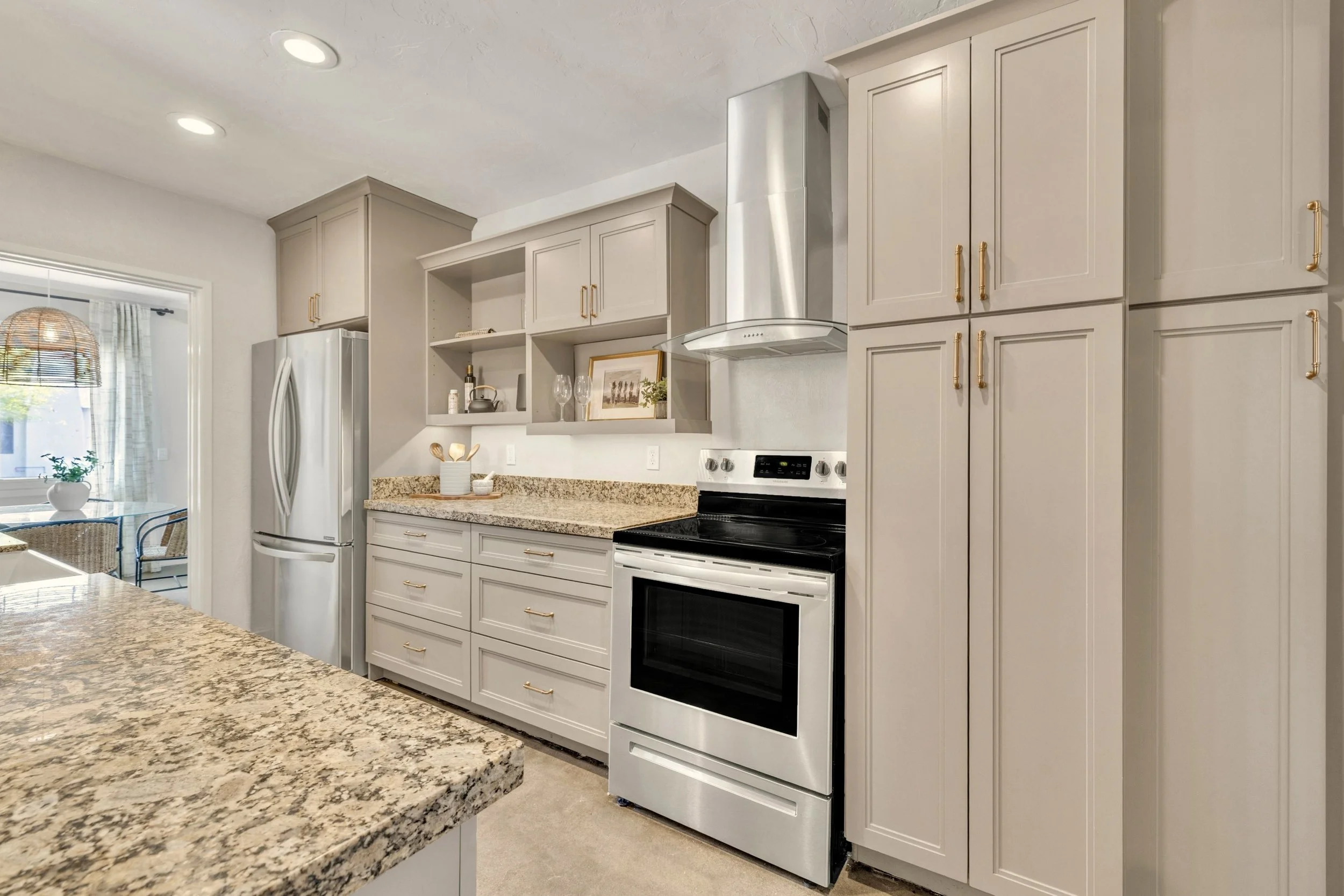This bright modern kitchen in Phoenix, AZ features granite countertops and stainless steel appliances, captured with expert real estate photography to highlight its spacious cabinetry and elegant design.