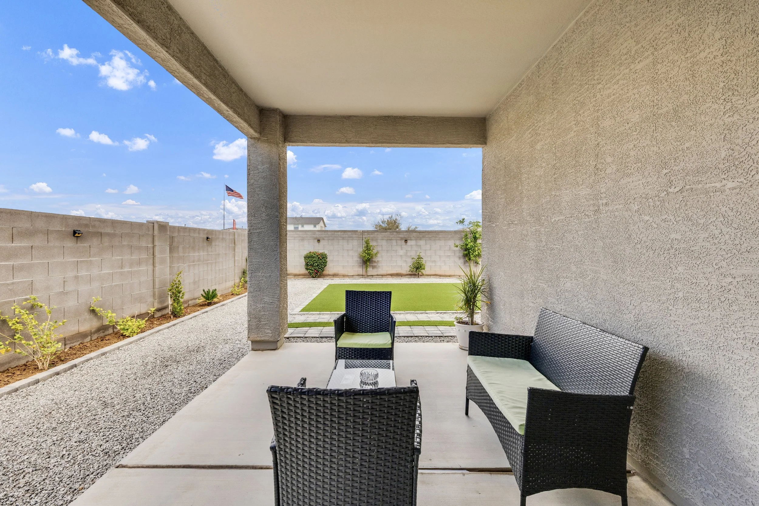 Covered patio with seating area overlooks a landscaped backyard in San Tan Valley, AZ, showcasing quality real estate photography for this comfortable outdoor space.