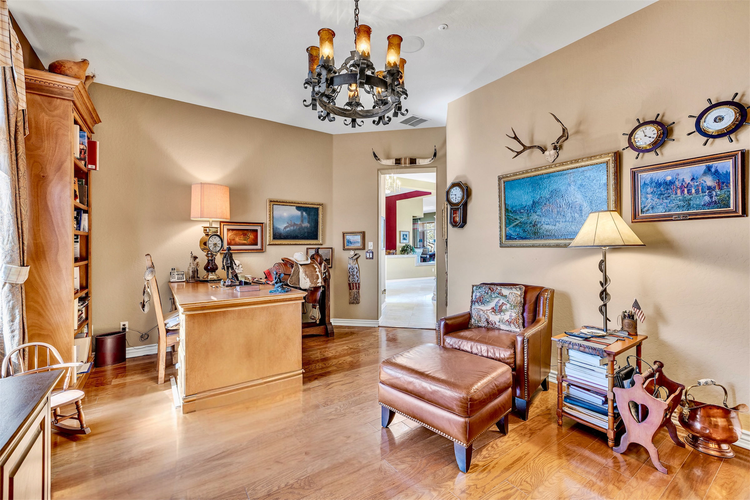 This cozy home office in Scottsdale, AZ features warm wood floors, leather seating, and tasteful decorations captured perfectly through professional real estate photography.