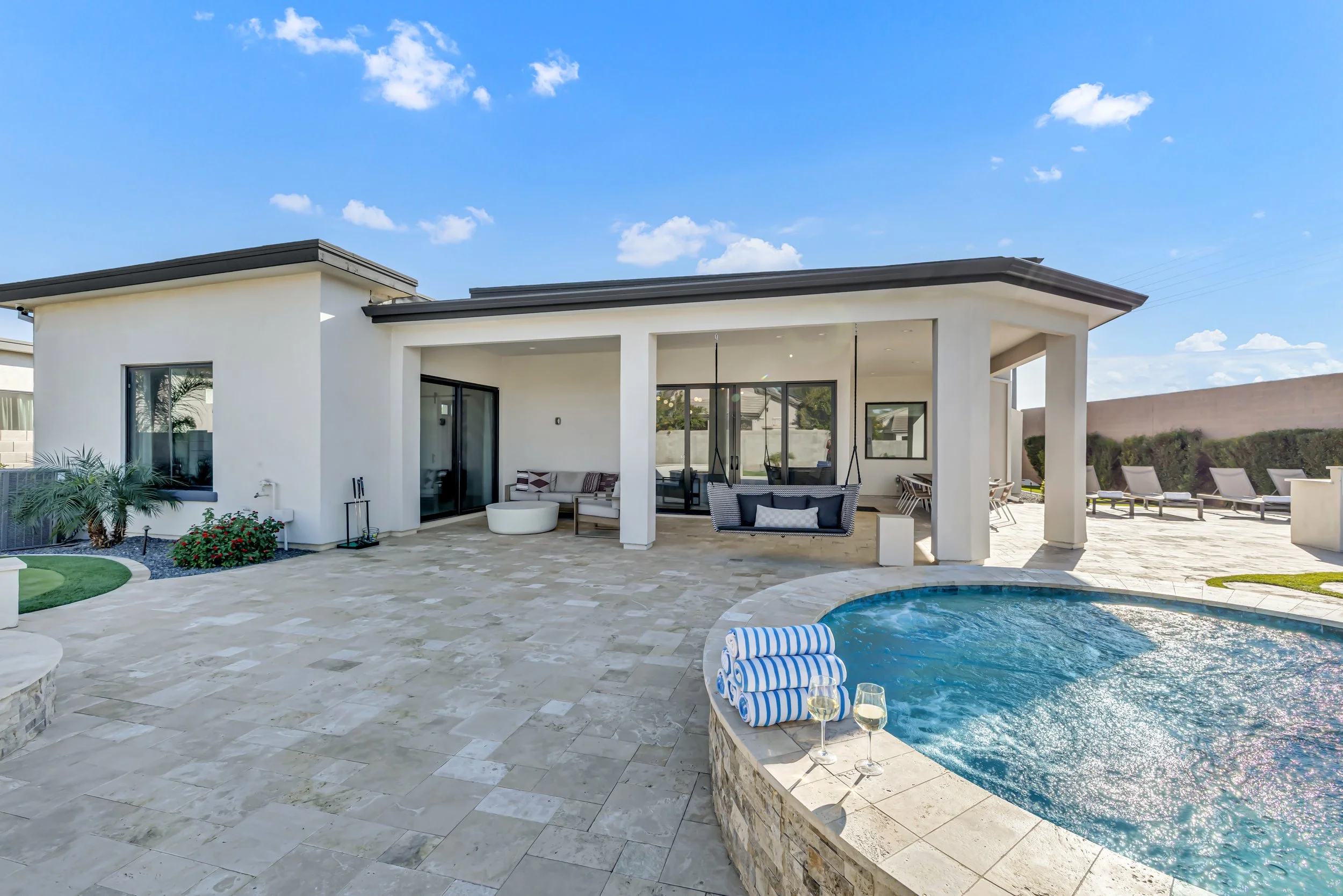Backyard patio and pool area with raised spa, swing chair, and stone paver flooring in Scottsdale, Arizona.