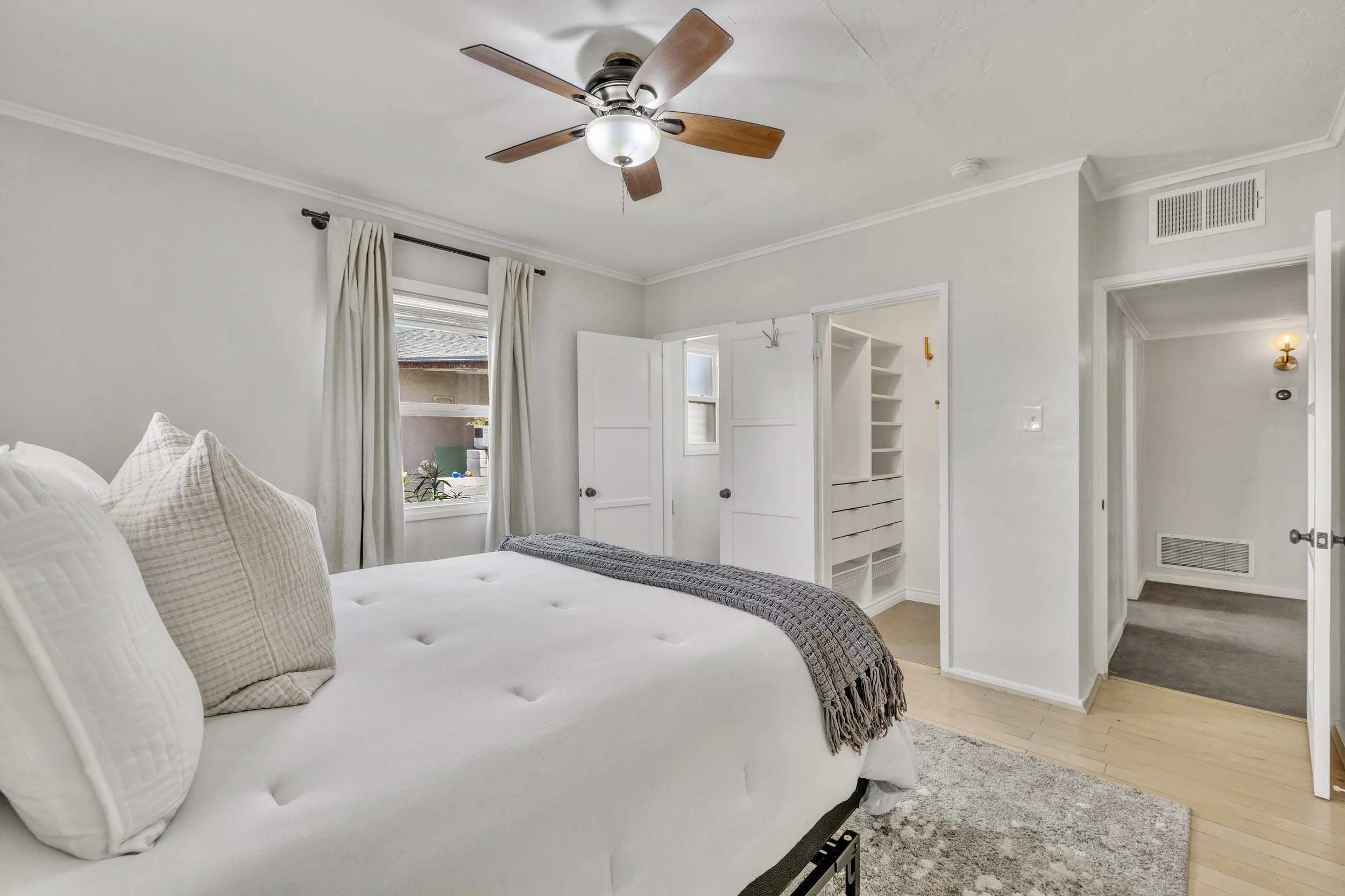Bright and airy bedroom with white walls, ceiling fan, and walk-in closet, showcased in professional real estate photography in Phoenix, AZ.