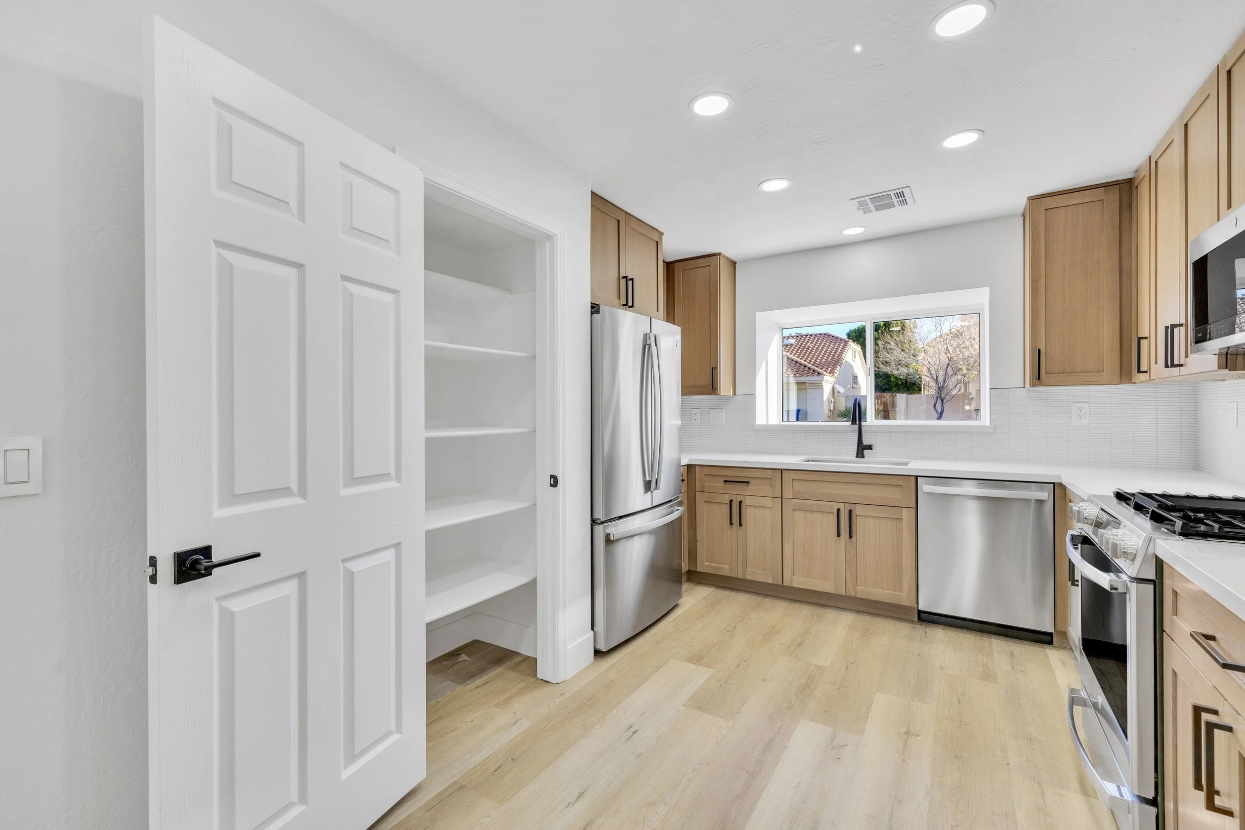 This modern kitchen in Chandler, AZ features wood cabinetry, stainless steel appliances, and a spacious pantry, perfectly captured by professional real estate photography for an inviting home presentation.