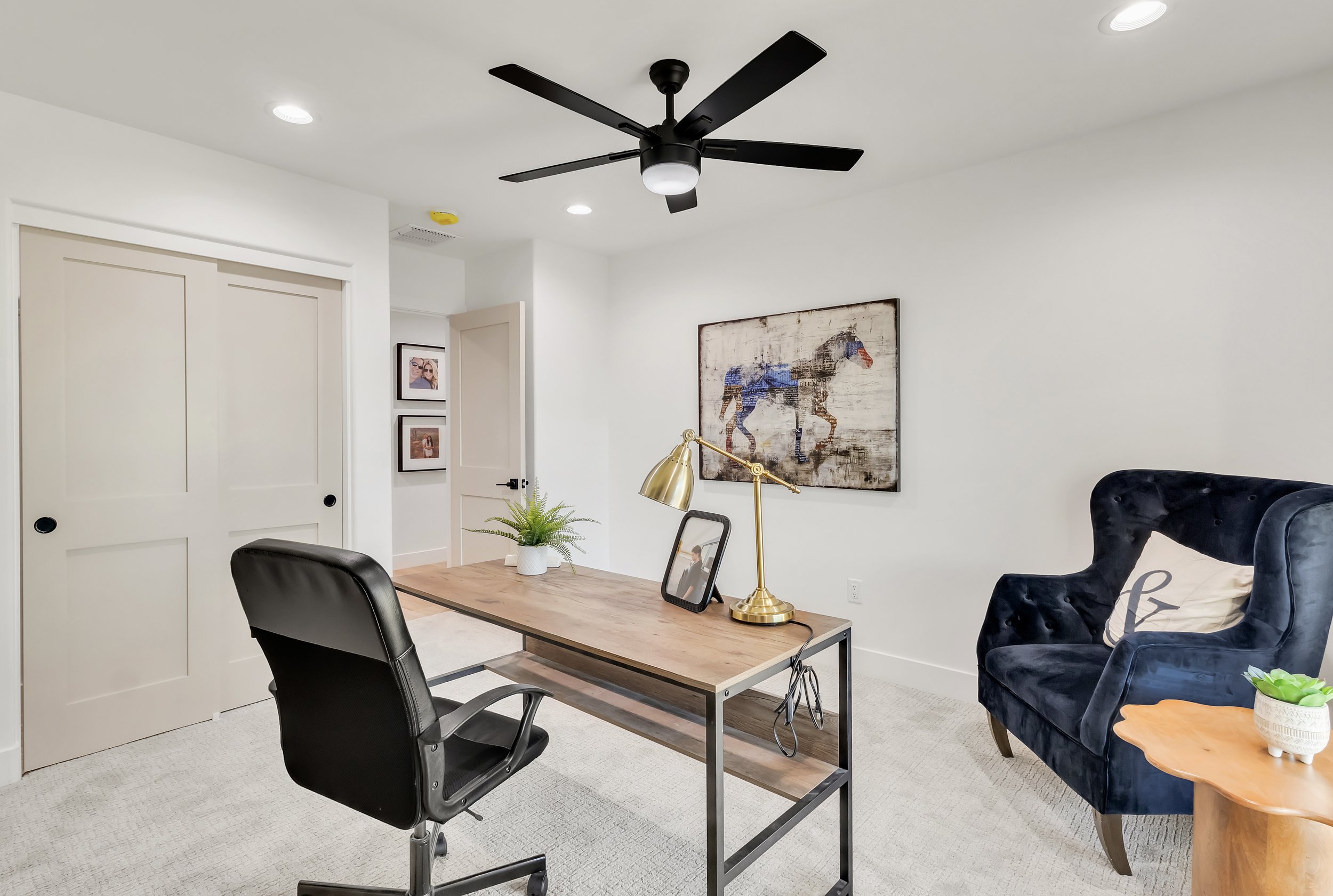 Home office in Phoenix, AZ featuring a modern black ceiling fan, minimalist desk, and neutral color palette.