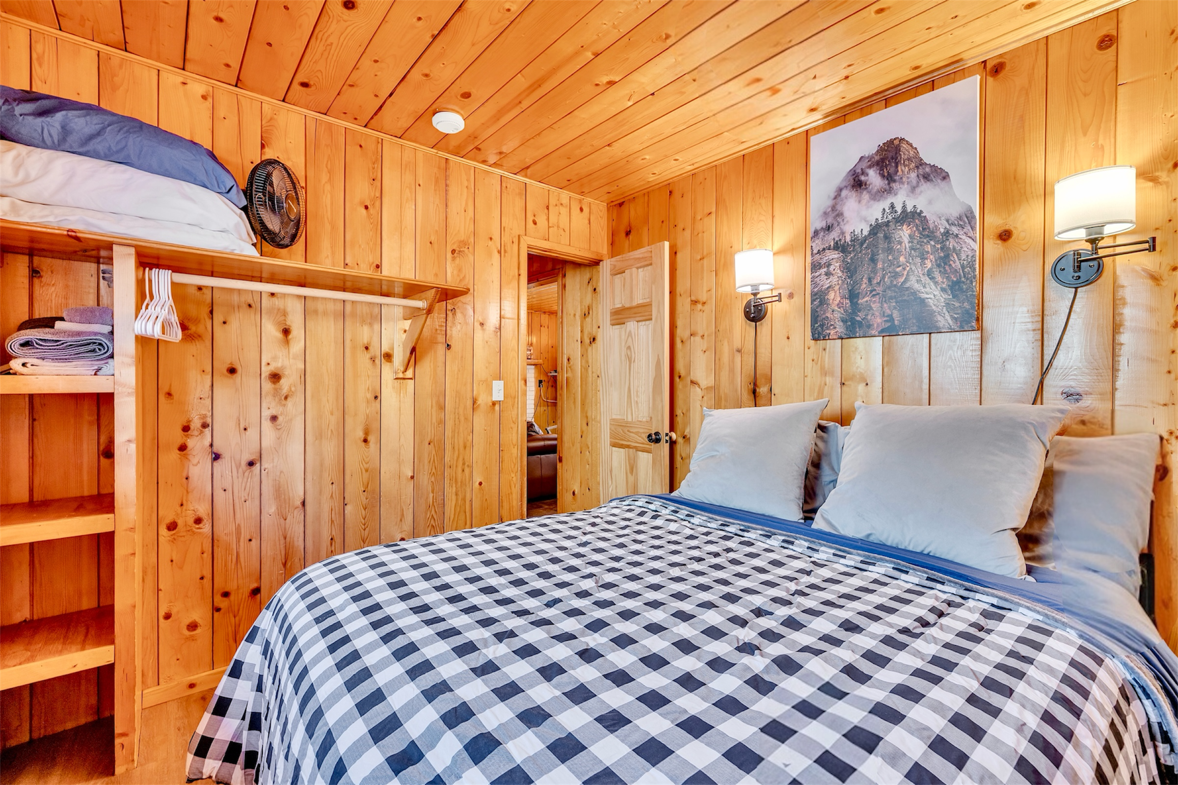 Cozy wood-paneled bedroom with queen bed and checkered bedding featured in real estate photography in Greer, AZ.