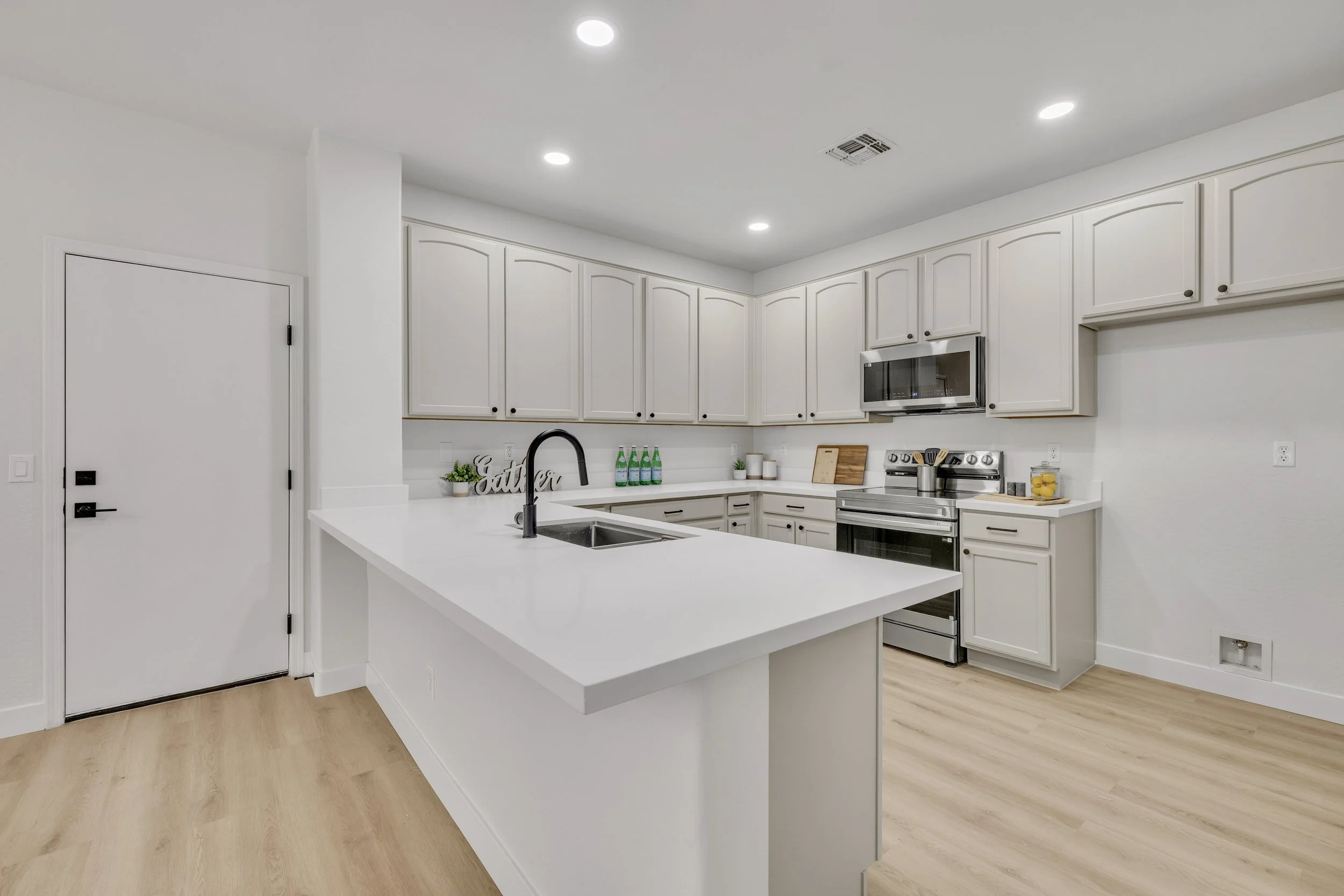 Bright modern kitchen with white cabinets and stainless appliances in Gilbert, AZ, showcased through professional real estate photography.