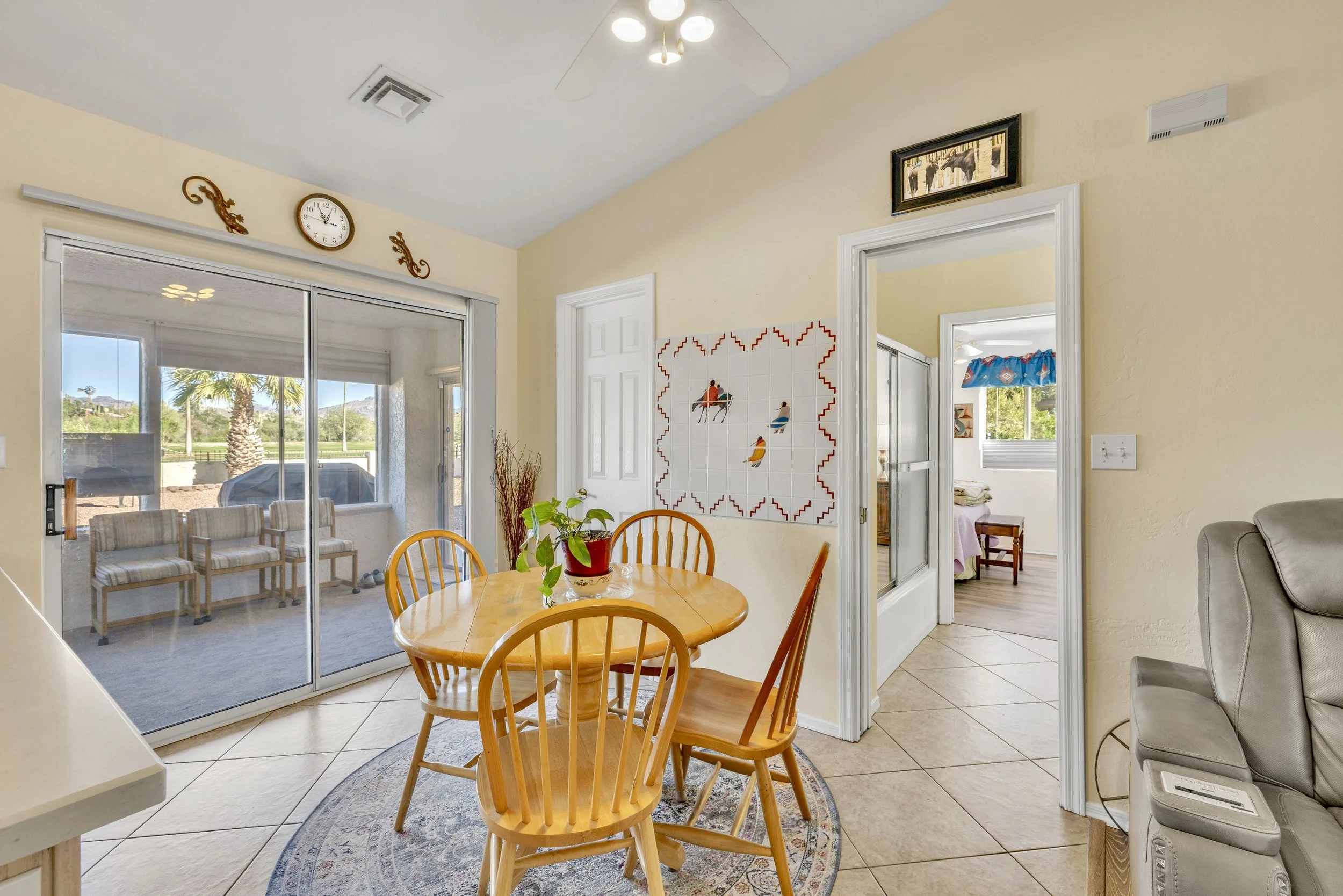 This inviting dining area features a wooden table and chairs with natural light from sliding glass doors in Queen Valley, AZ, captured using expert real estate photography to highlight the cozy living space.