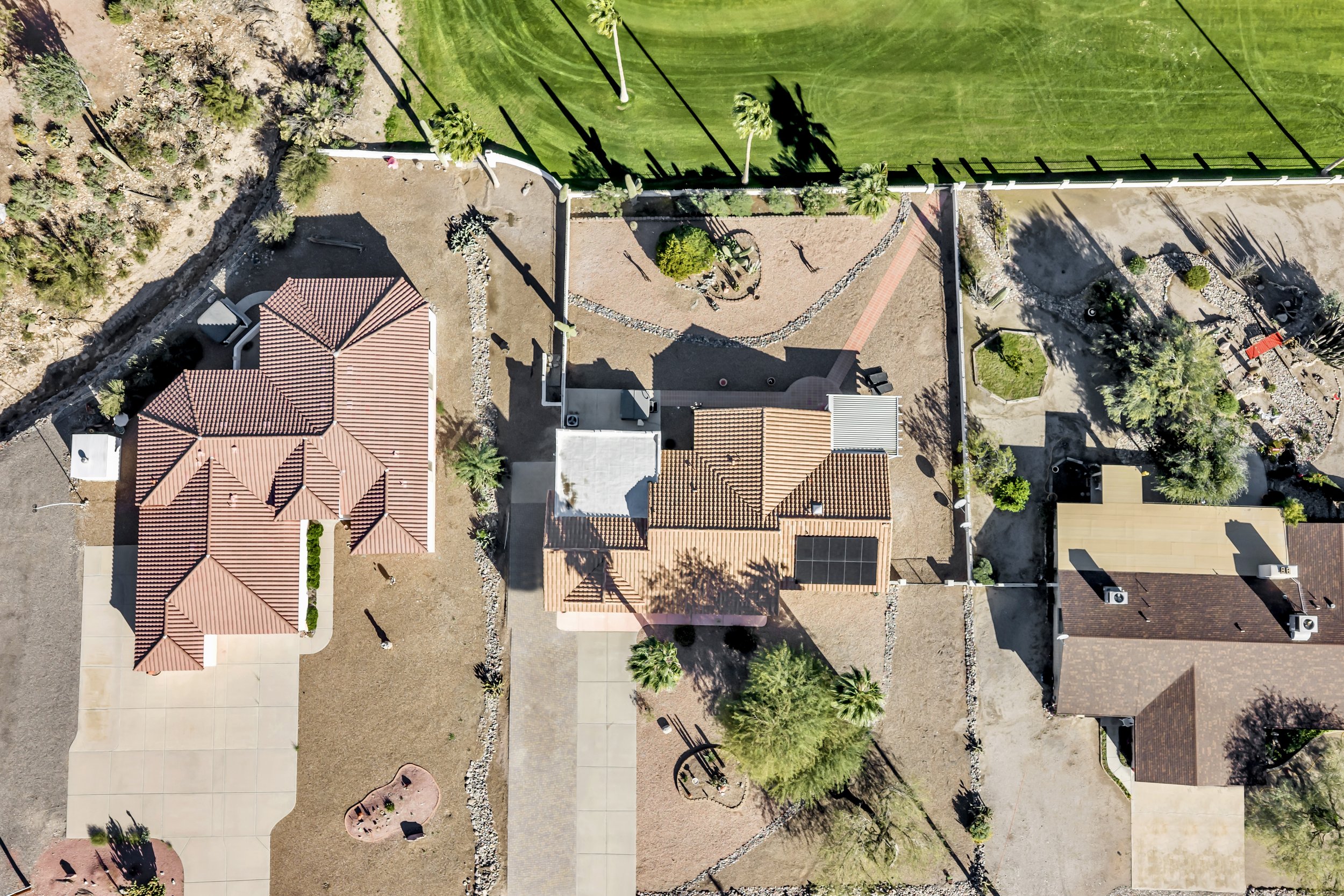 Drone photo of an Arizona golf course neighborhood showing residential lots, fairways, desert terrain, and mountain views.