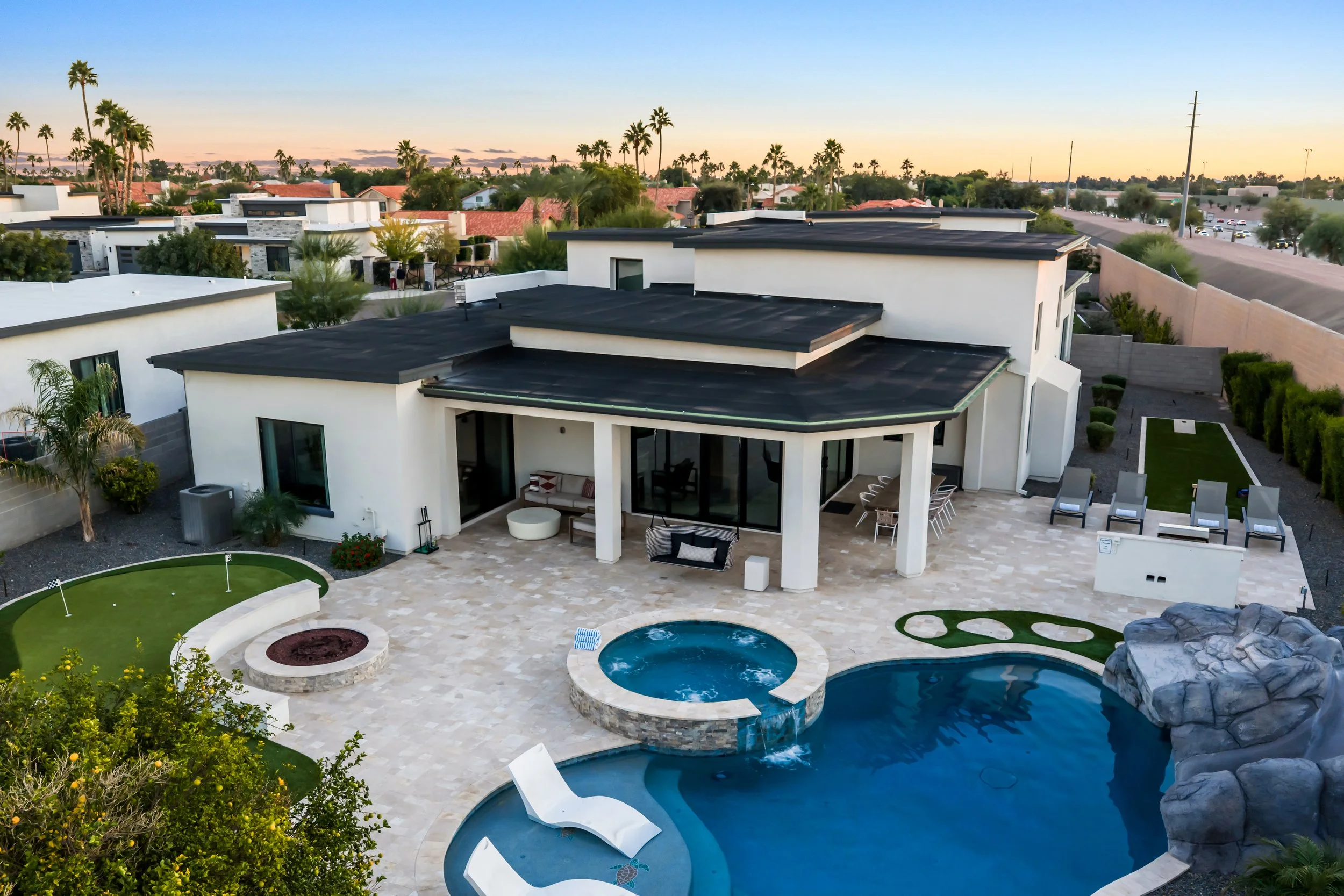 Aerial view of backyard with pool, waterfall rock feature, spa, and putting greens in Scottsdale, Arizona.