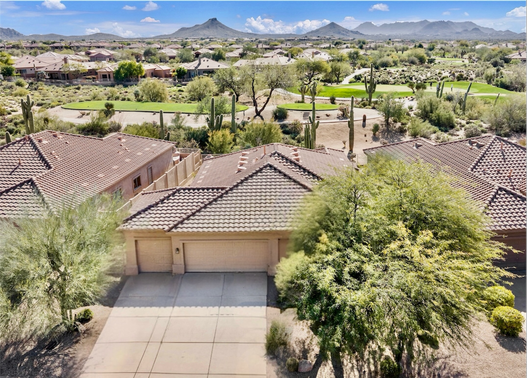 Aerial real estate photography showcasing residential homes with tiled roofs overlooking a lush golf course and desert landscape in Scottsdale, AZ.