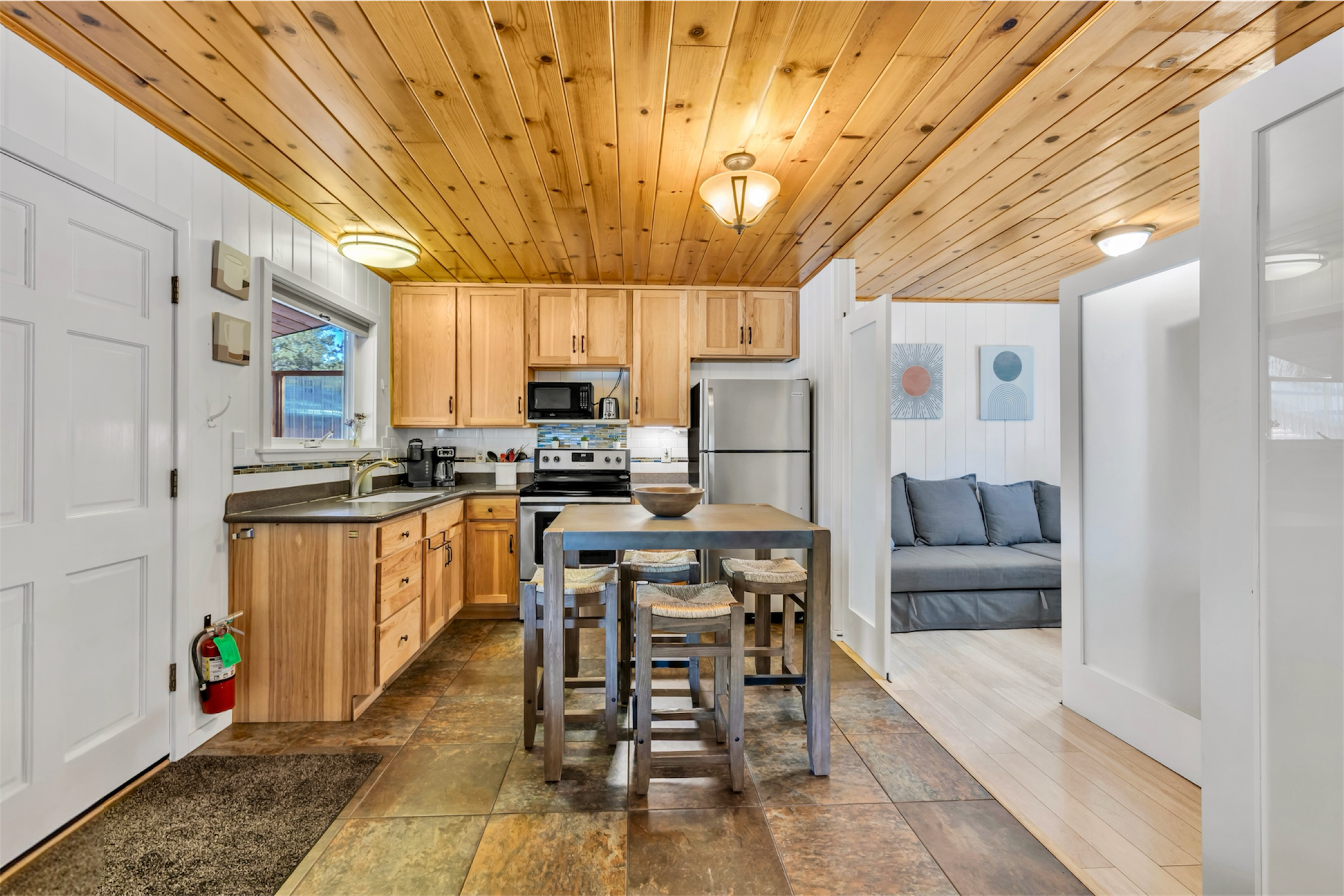 This cozy kitchen and dining area with natural wood ceiling and modern appliances showcases charming real estate photography in Greer, AZ.