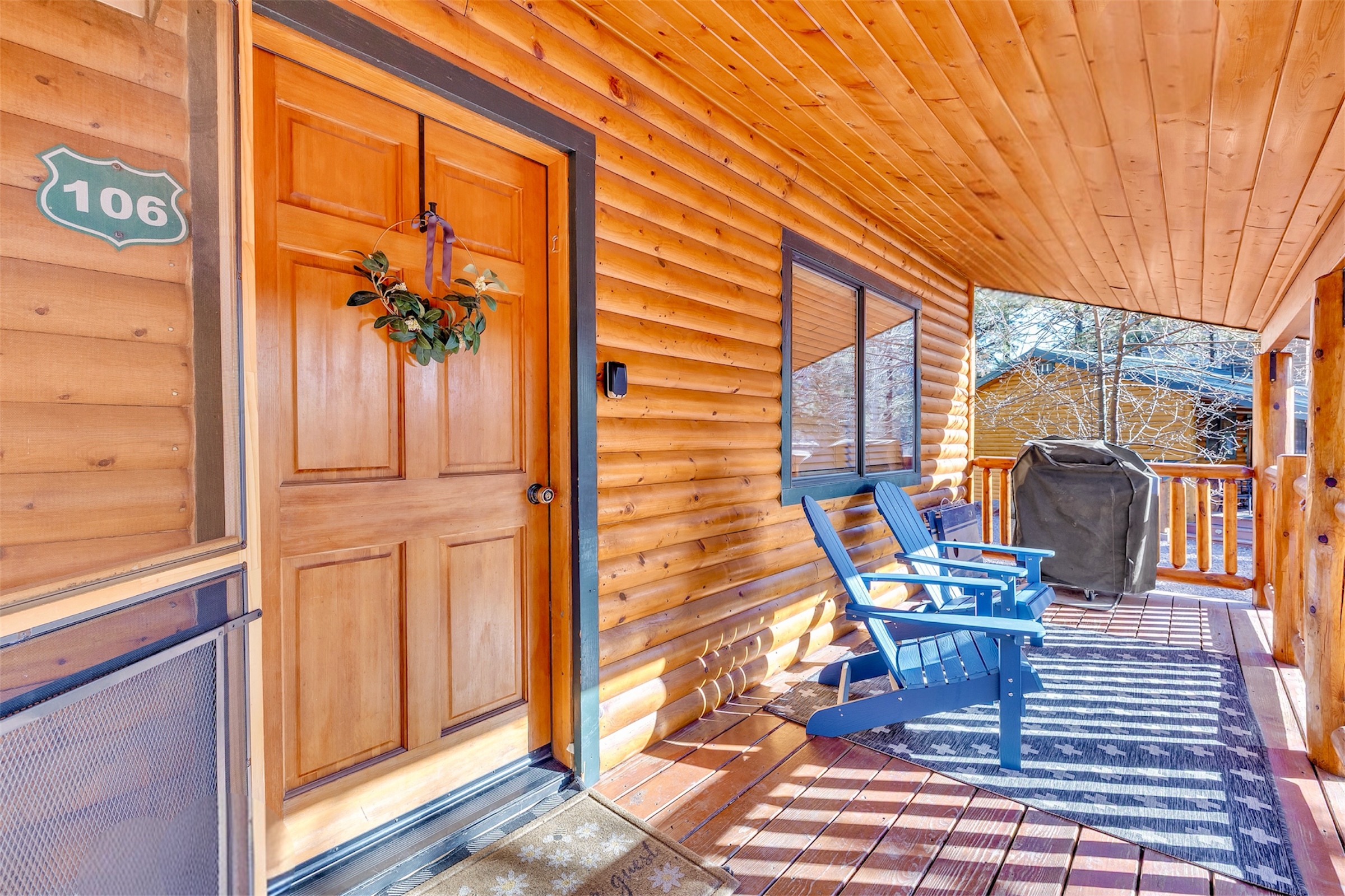 This inviting wooden porch with blue chairs and a grill highlights cozy outdoor living, captured in quality real estate photography in Greer, AZ.