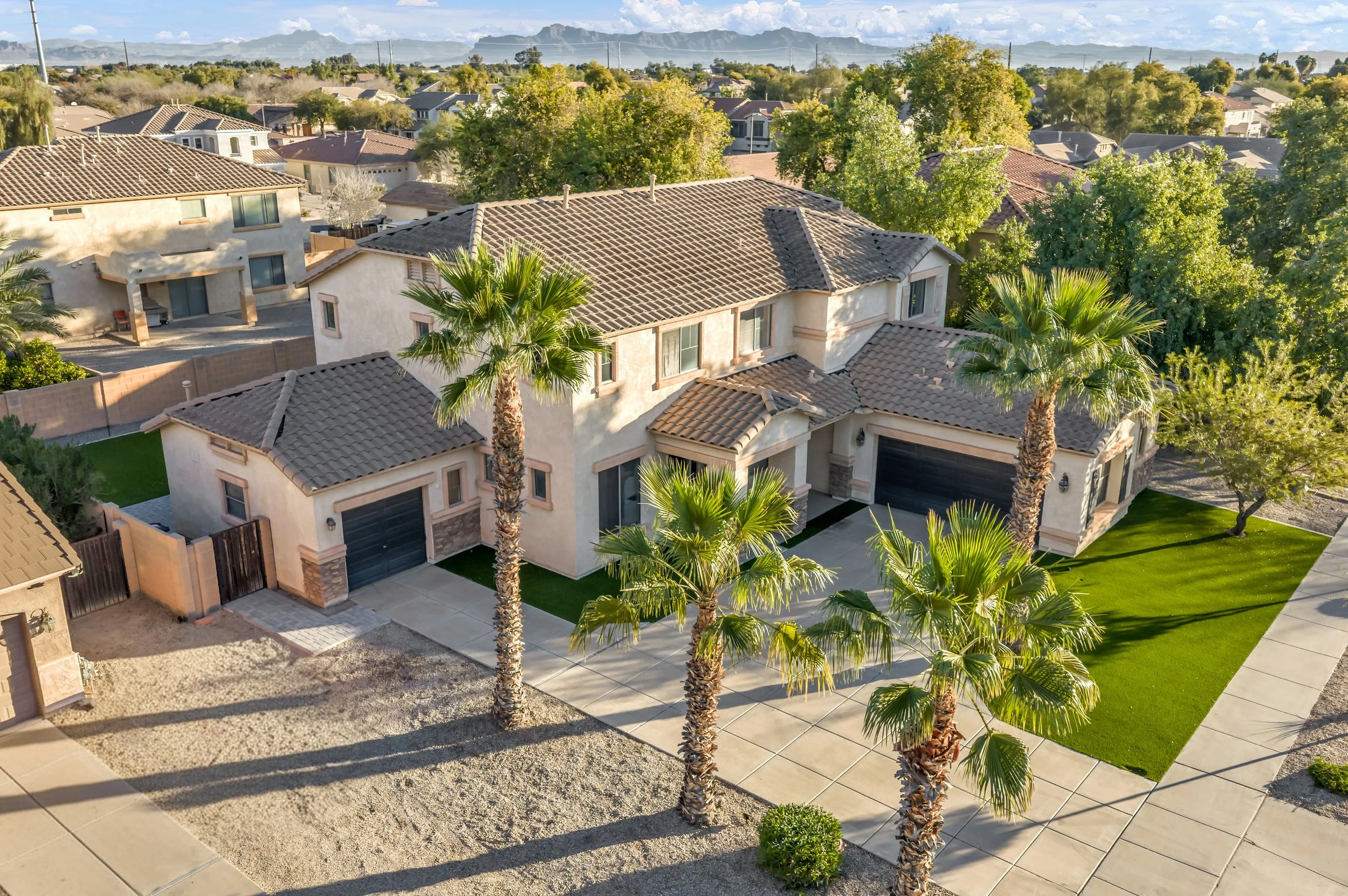 Beautiful Mediterranean-style home with palm trees and well-maintained landscaping in Queen Creek, AZ, showcasing spacious driveway and garage space for comfortable living.
