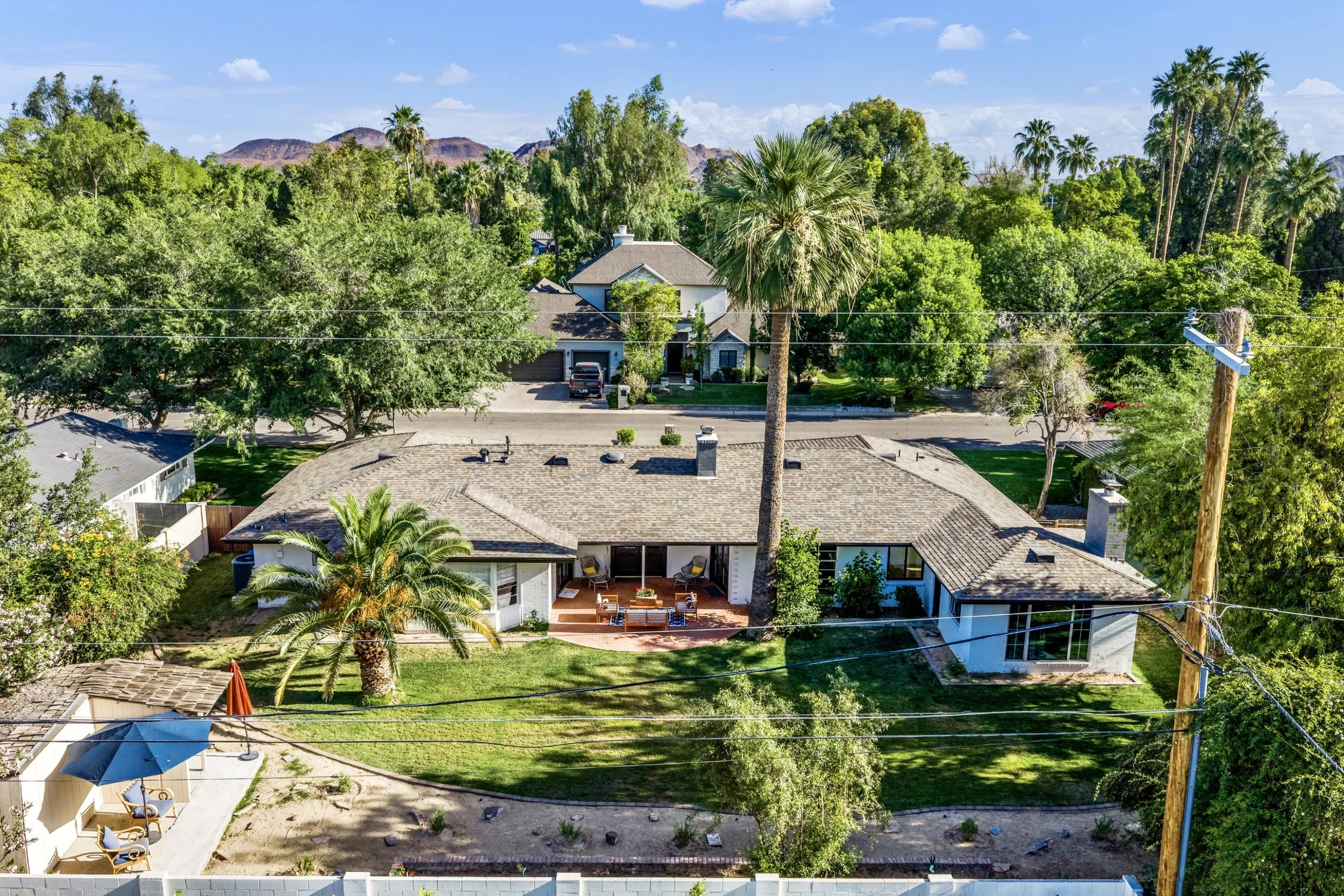 This aerial real estate photography showcases a spacious residential home with a large backyard and lush greenery in Phoenix, AZ, highlighting the serene neighborhood on E Northview Ave.