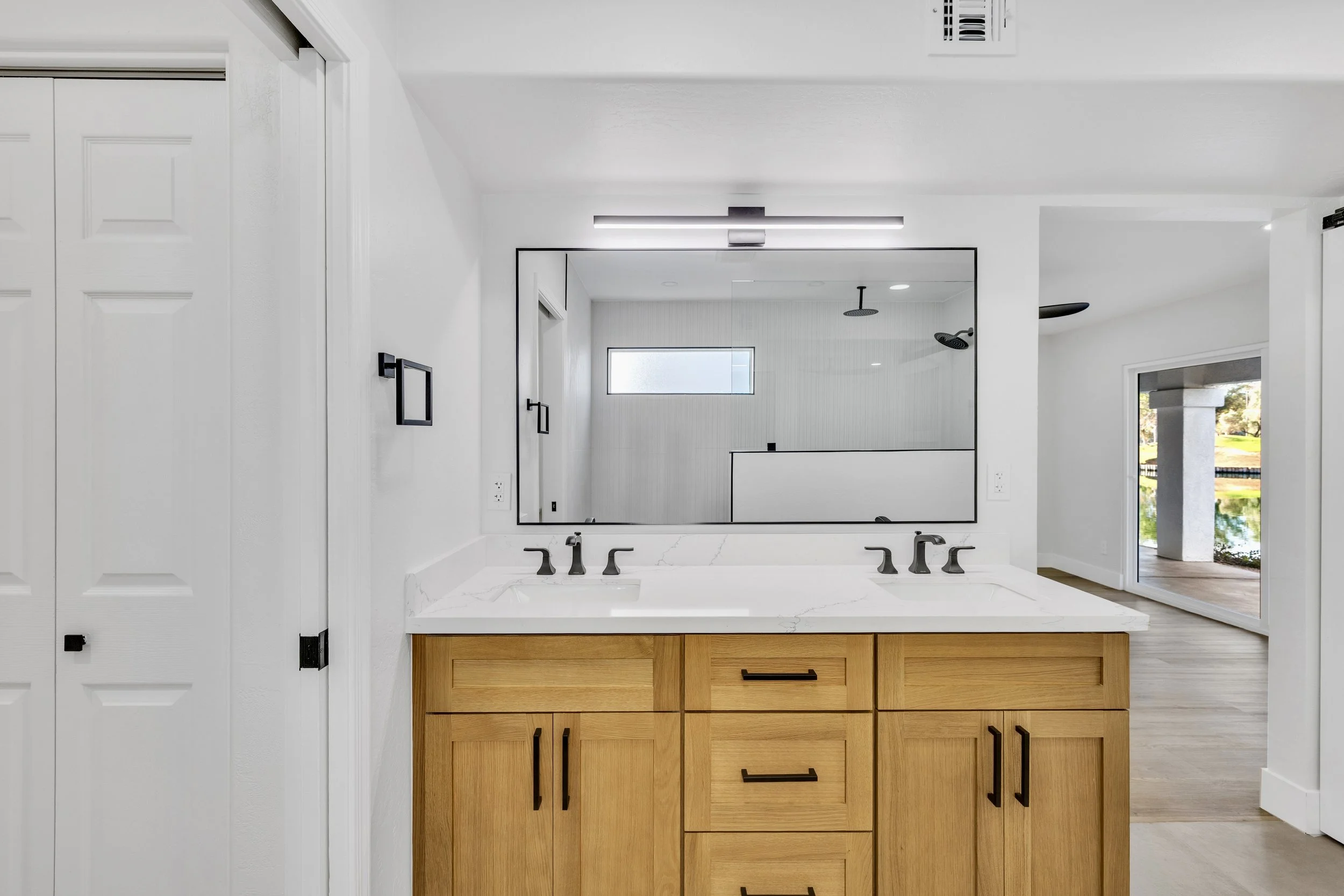 This modern bathroom in Chandler, AZ features a wood cabinet dual sink setup and is captured with professional real estate photography showcasing clean design and natural lighting.