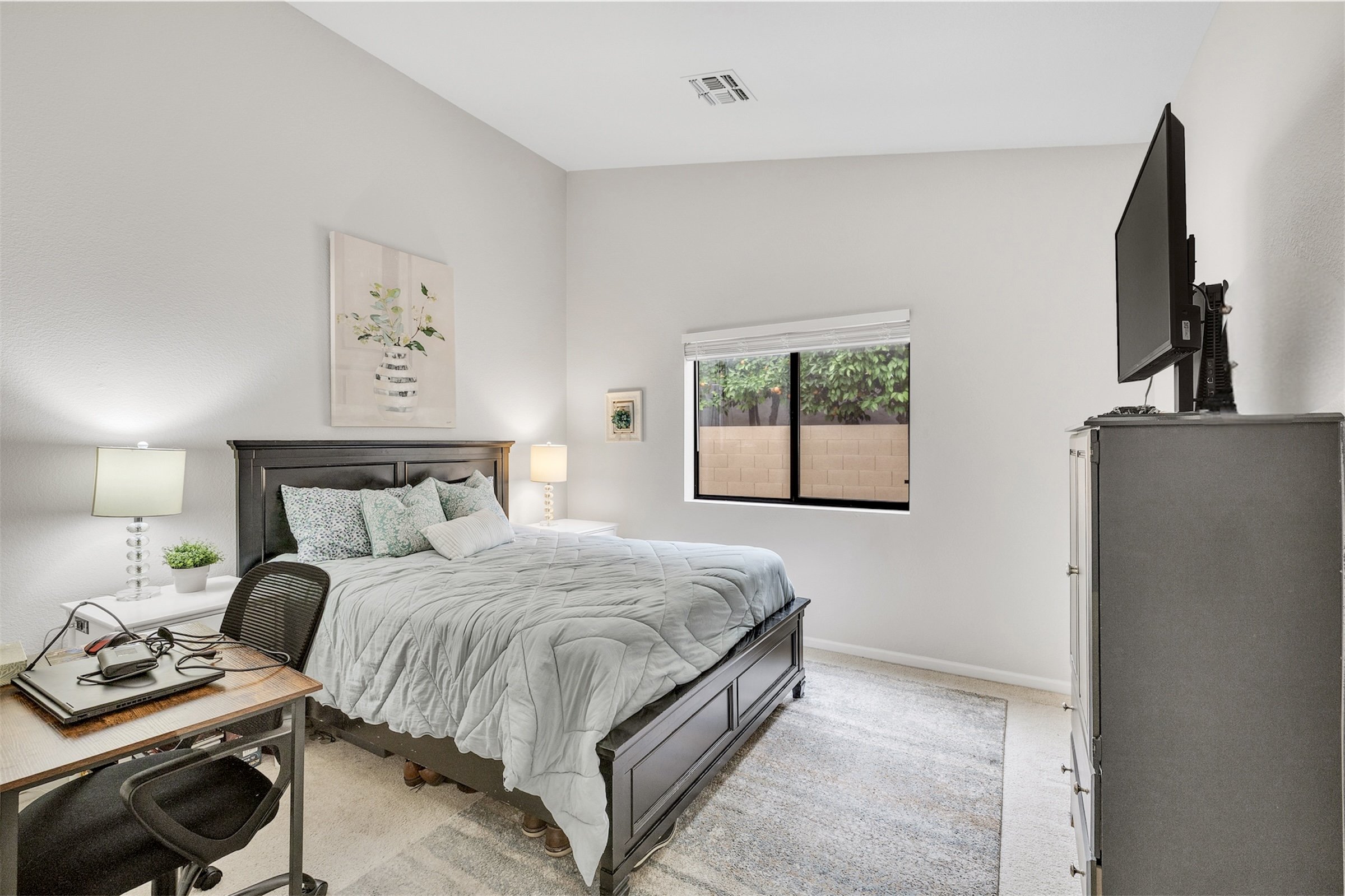 Bright bedroom interior with modern furniture and a window view showcasing real estate photography in Goodyear, AZ.