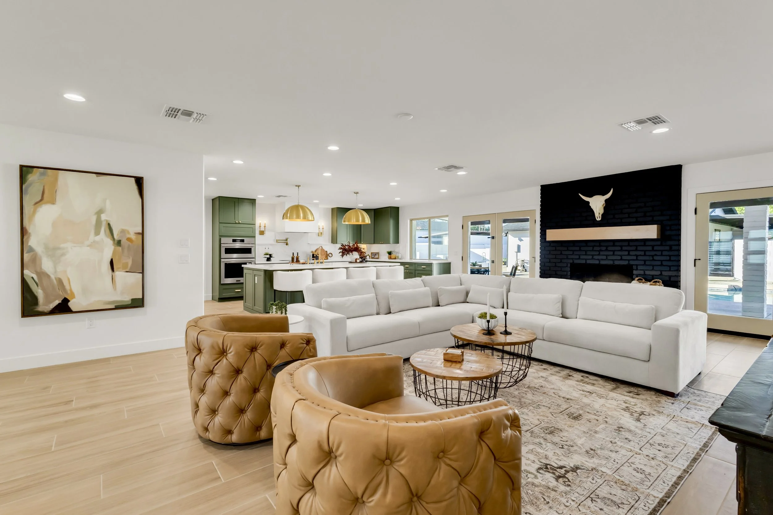 Inviting living area in Phoenix, AZ with tan tufted leather chairs, black brick fireplace, and wood-look tile flooring.