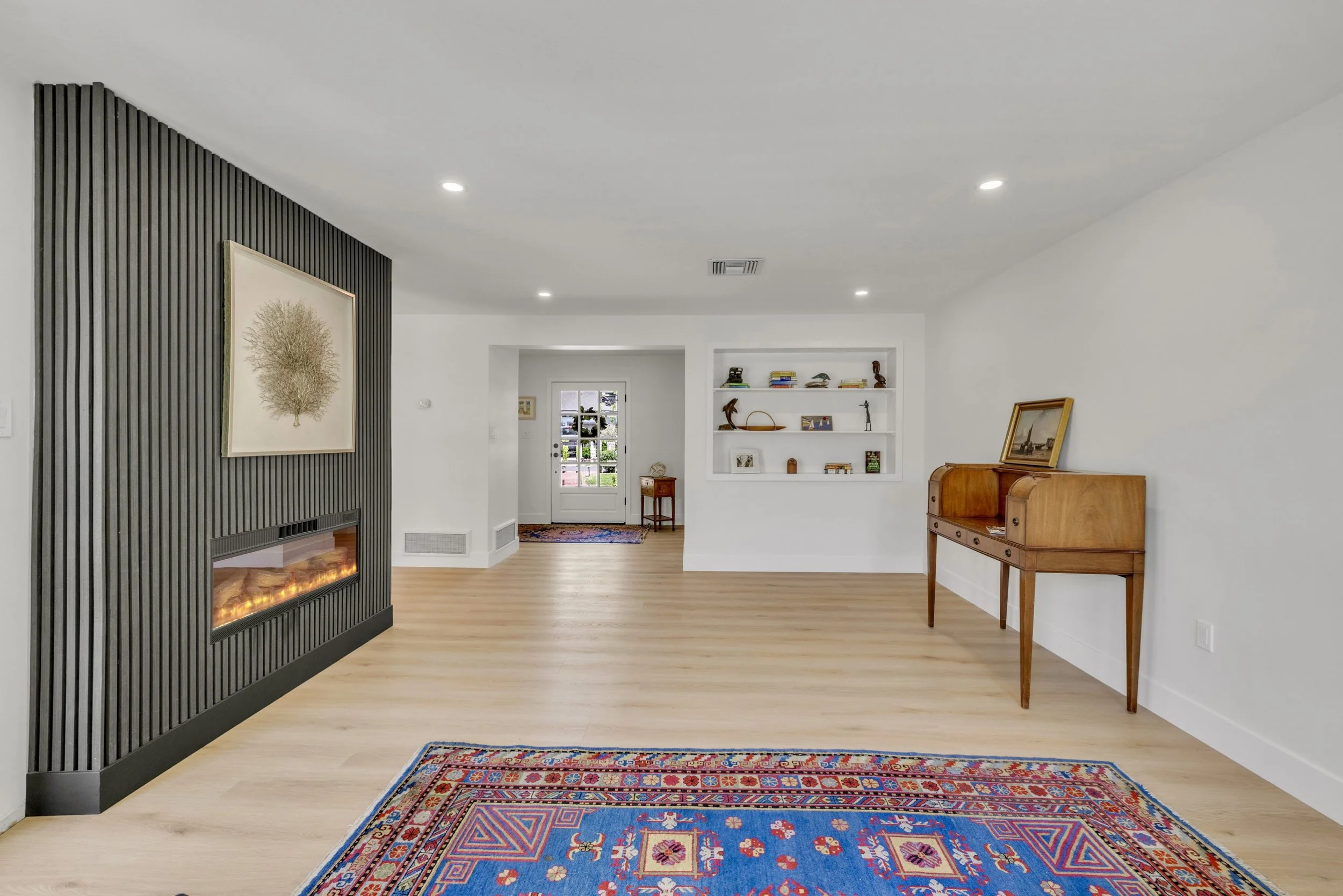 This modern living room in Phoenix, AZ features a stylish gas fireplace, wooden flooring, and built-in shelving, perfect for showcasing your home with professional real estate photography.