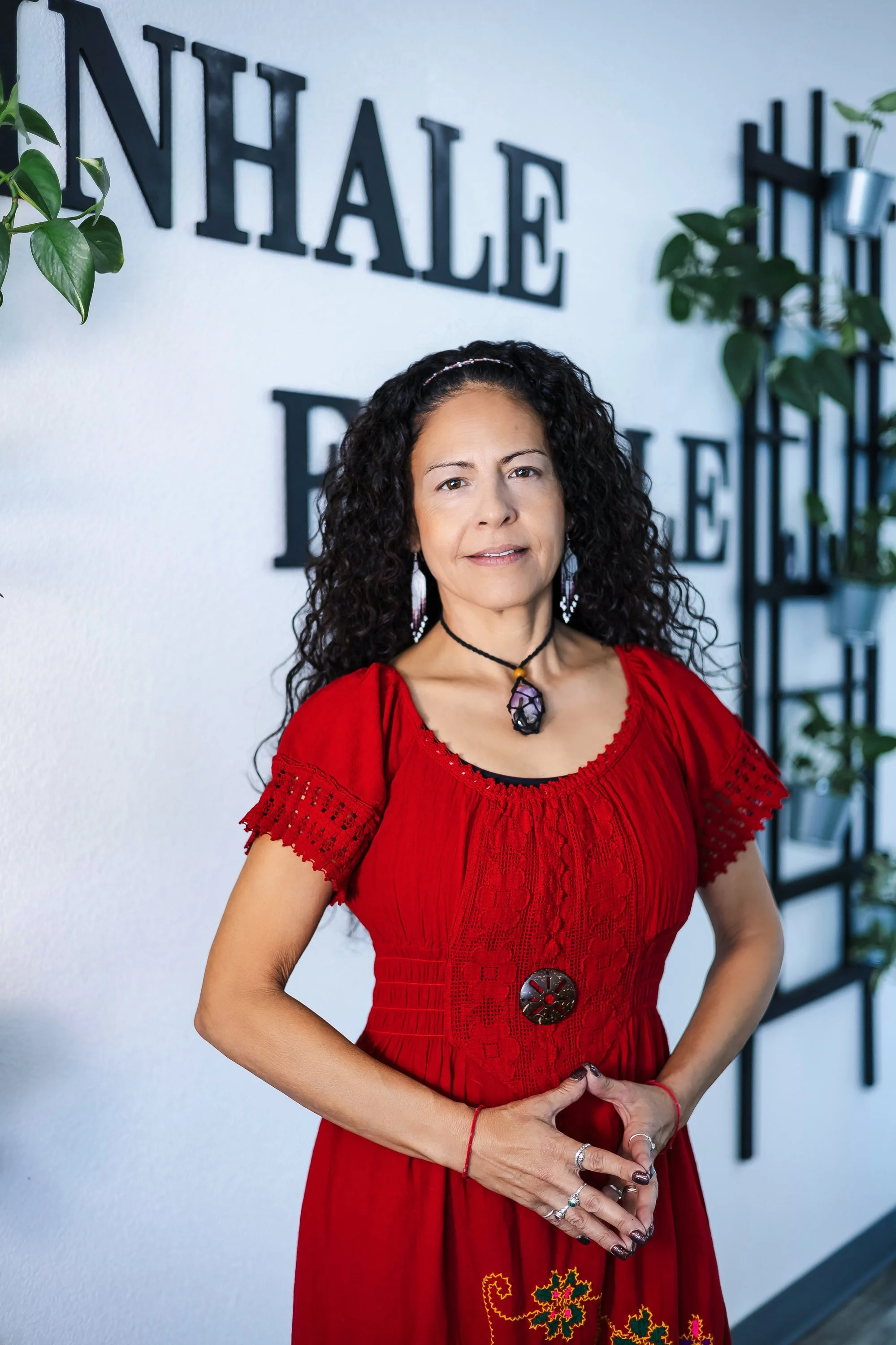 A woman in a red dress poses indoors with a calm expression in East Valley, AZ, capturing an authentic moment for lifestyle branding photography.
