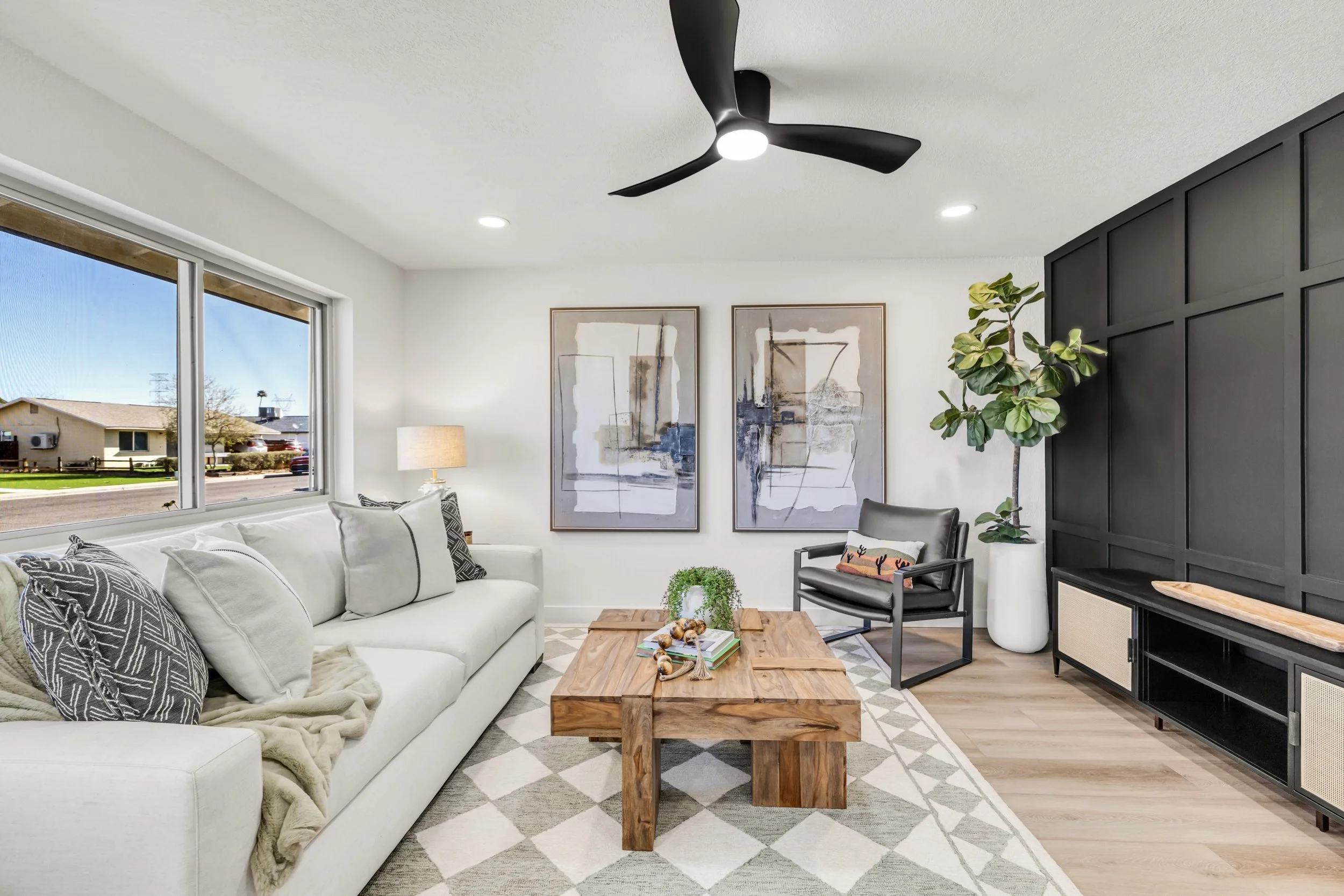 This modern living room in Mesa, AZ features stylish decor, a large window with natural light, and attractive furnishings, captured with expert real estate photography.