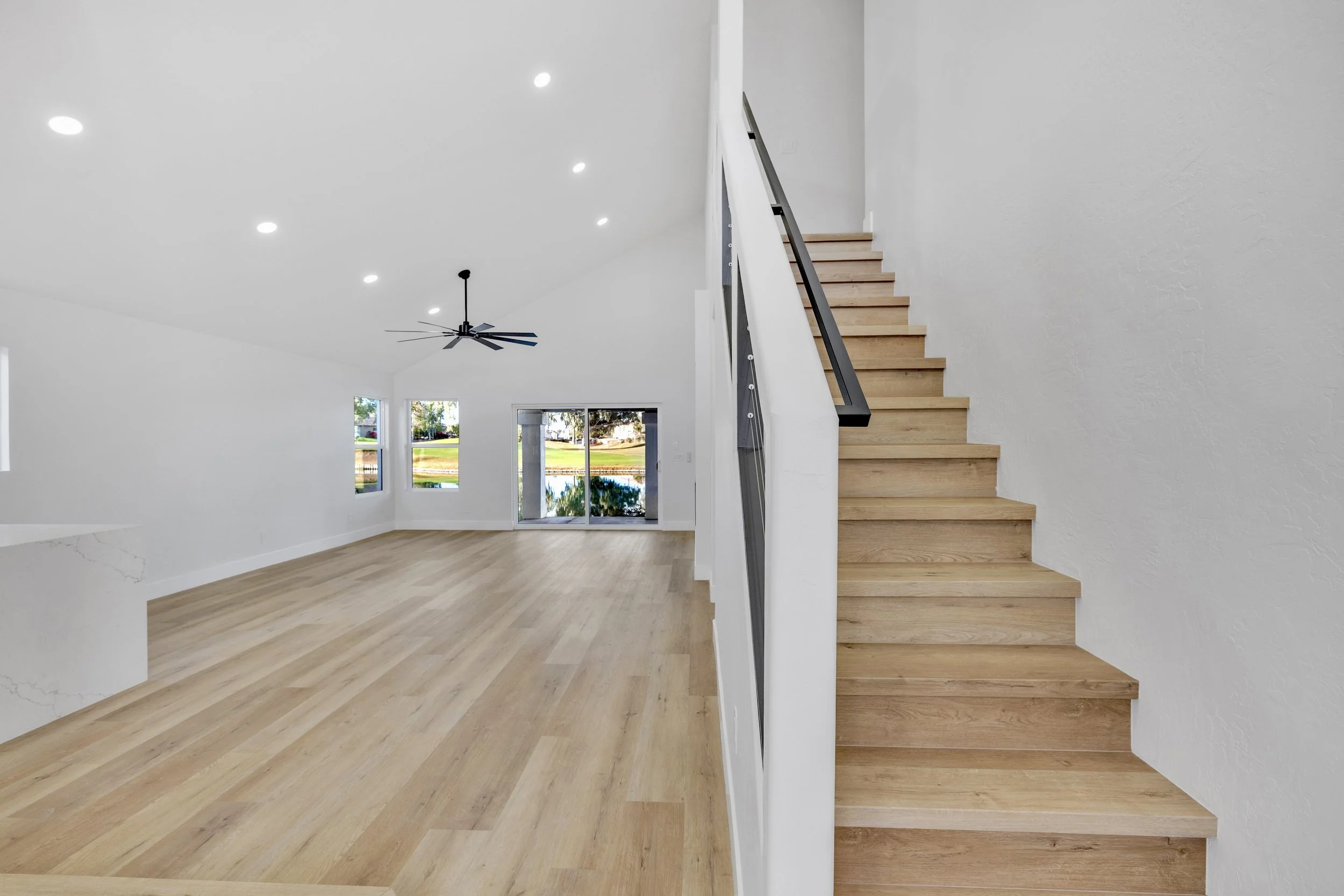 This modern home in Chandler, AZ features an open living room with wooden stairs, perfect for real estate photography to showcase spacious and bright interiors with beautiful outdoor views.