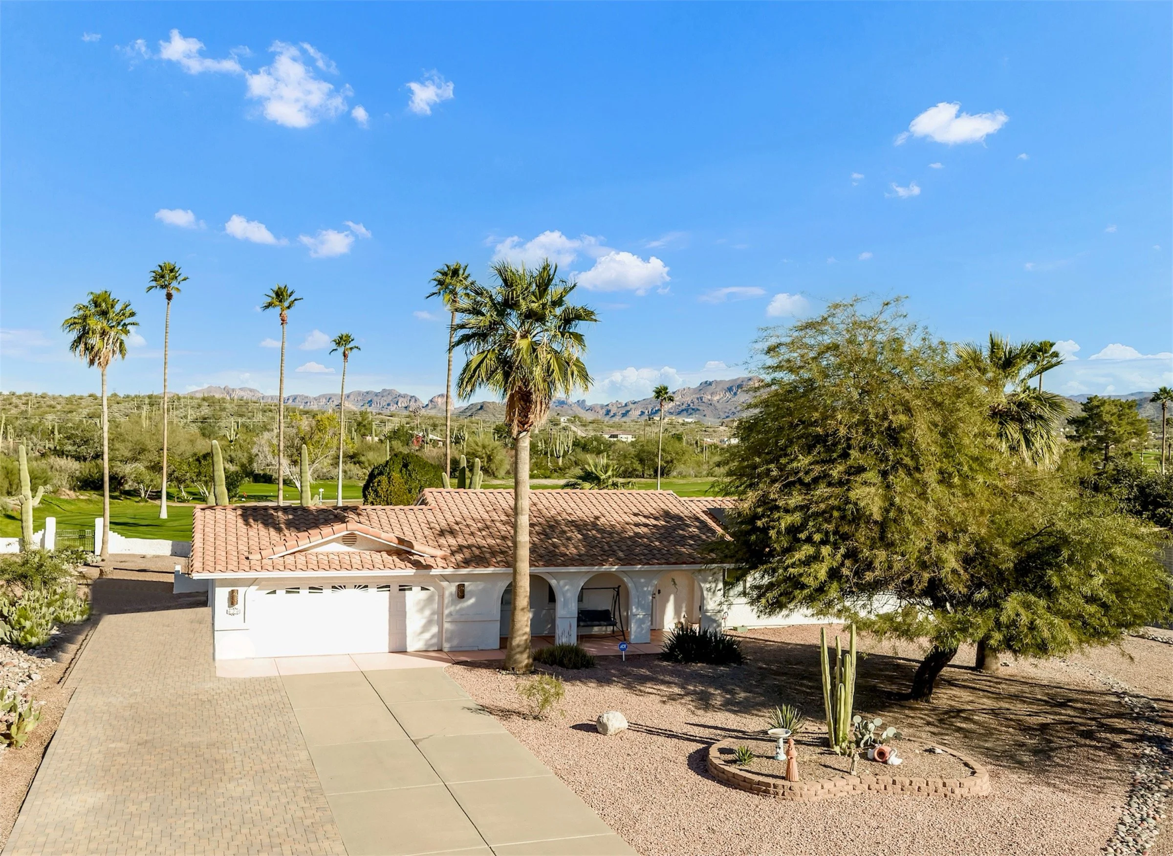 Stunning exterior real estate photography of a single-story home with desert landscaping in Queen Valley, AZ, highlighting the spacious driveway and scenic mountain views.
