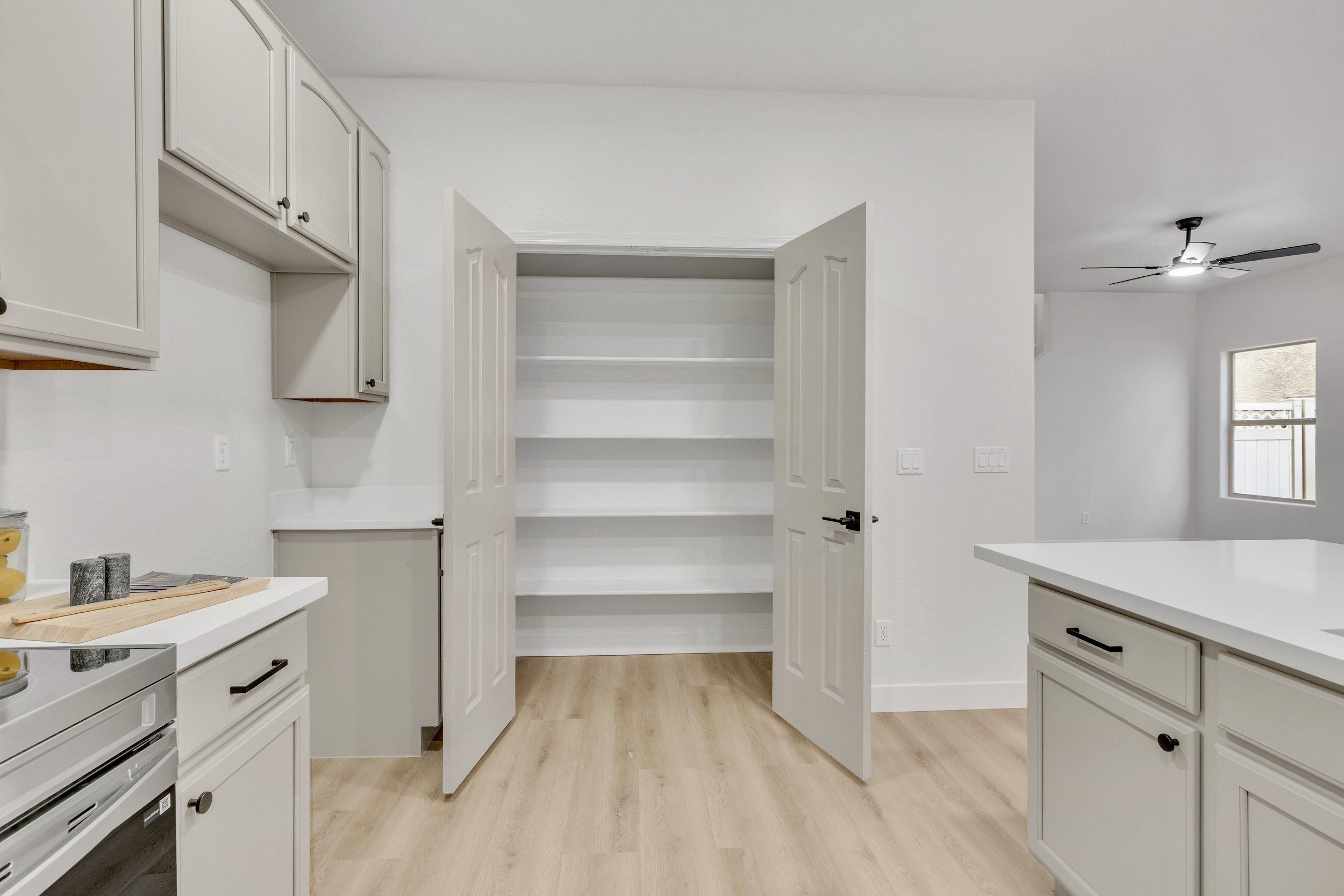 This modern kitchen in Gilbert, AZ features an open pantry, sleek cabinetry, and light wood flooring, captured through professional real estate photography highlighting the home’s spacious layout.