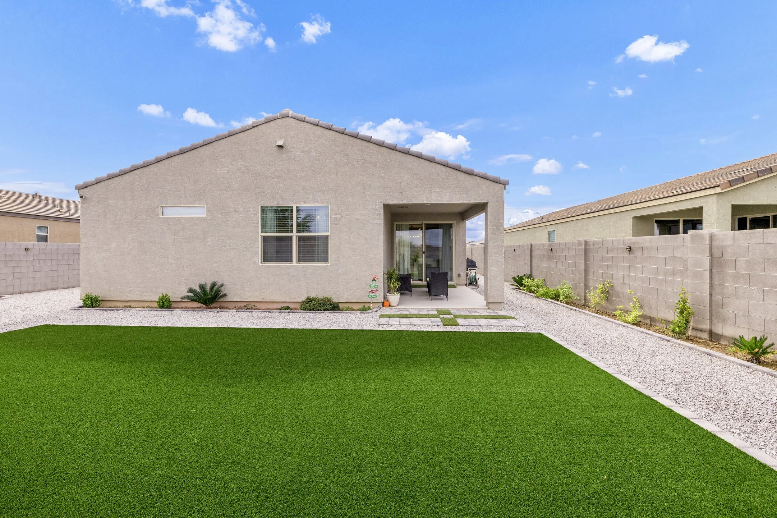 This image showcases a clean backyard with green artificial turf and a covered patio area in San Tan Valley, AZ, perfect for real estate photography highlighting outdoor living spaces.