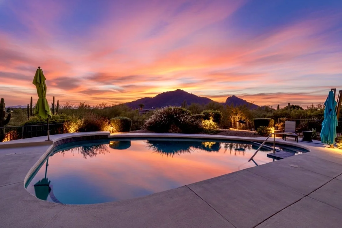 Stunning real estate photography captures a backyard pool at sunset with desert landscaping and mountain views in Paradise Valley, AZ.
