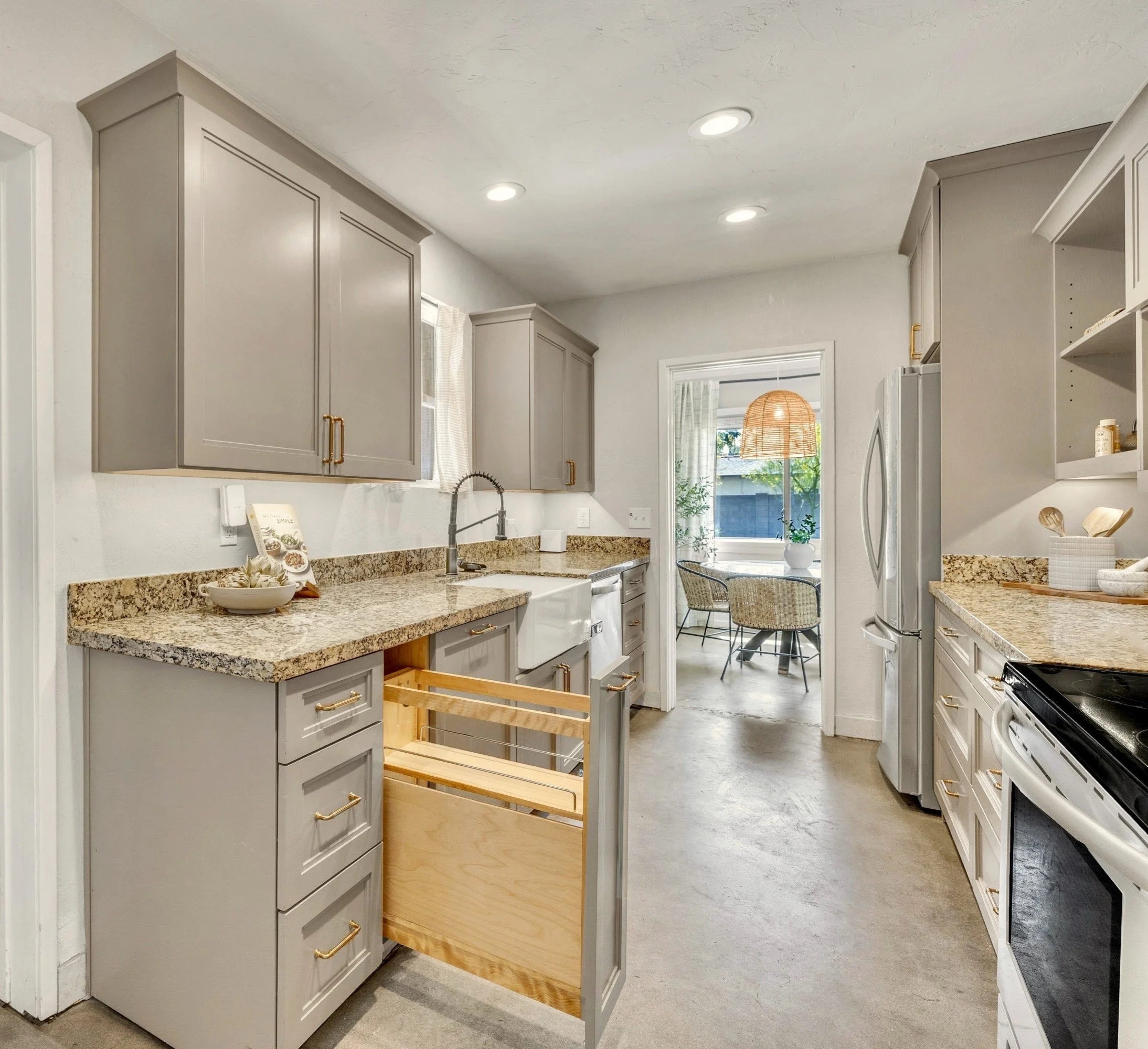 This bright modern kitchen in Phoenix, AZ features granite countertops, a pull-out cabinet, and stainless steel appliances, perfectly captured with real estate photography.