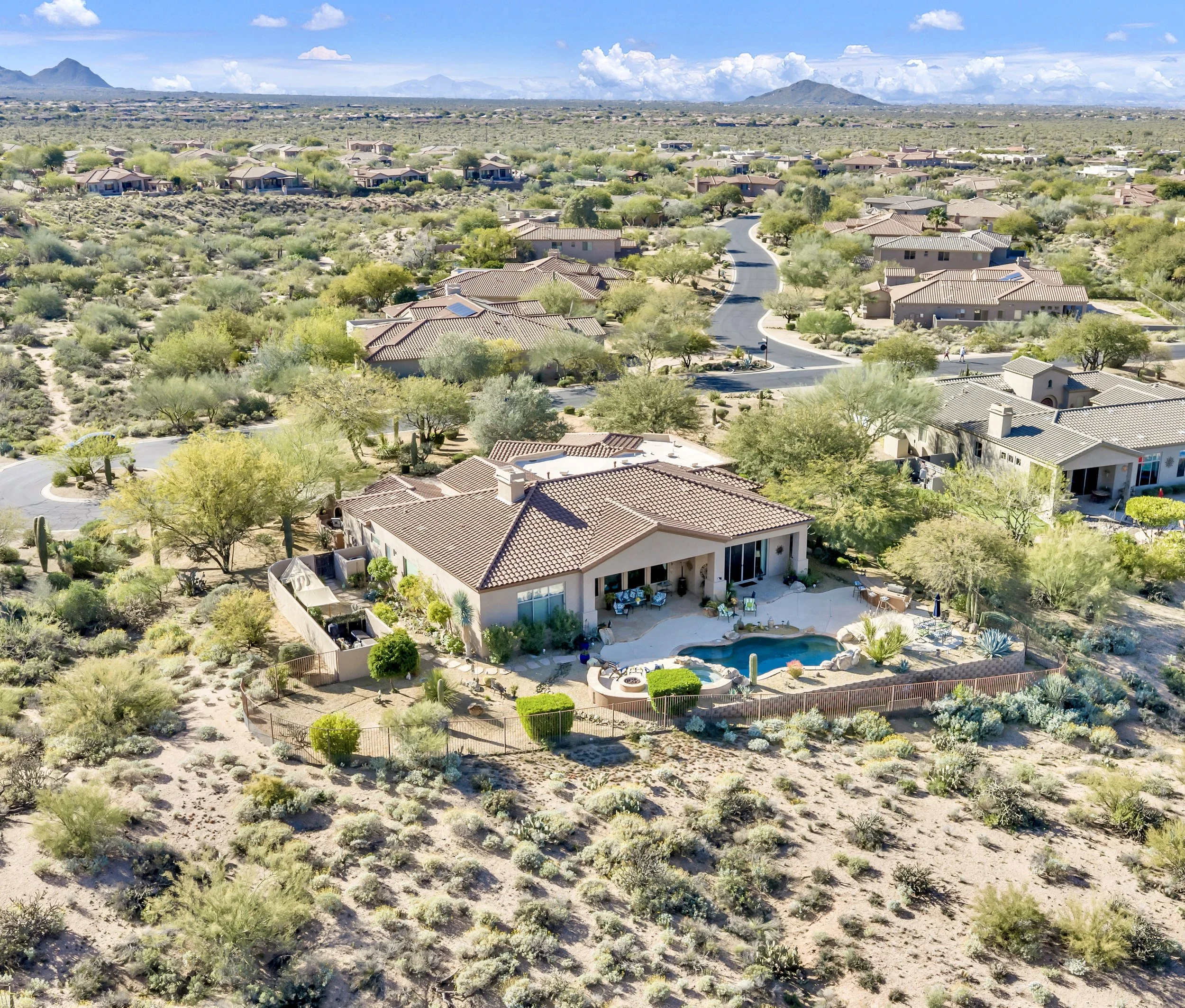 This aerial view showcases a beautiful suburban home with a pool surrounded by desert landscape in Scottsdale, AZ, highlighting expert real estate photography.