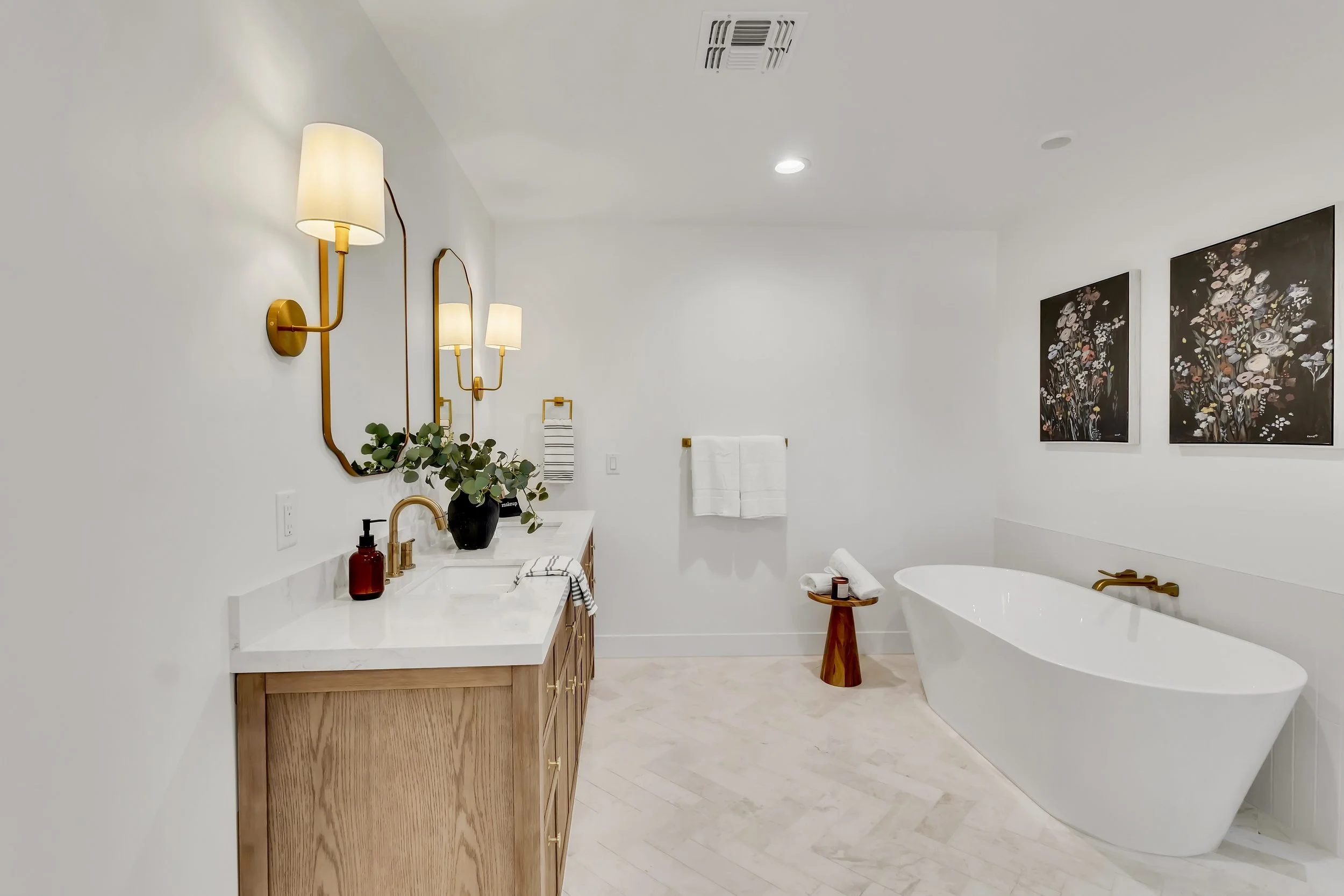 Stylish primary bathroom in Phoenix, AZ with freestanding soaking tub, gold wall sconces, and contemporary vanity design.