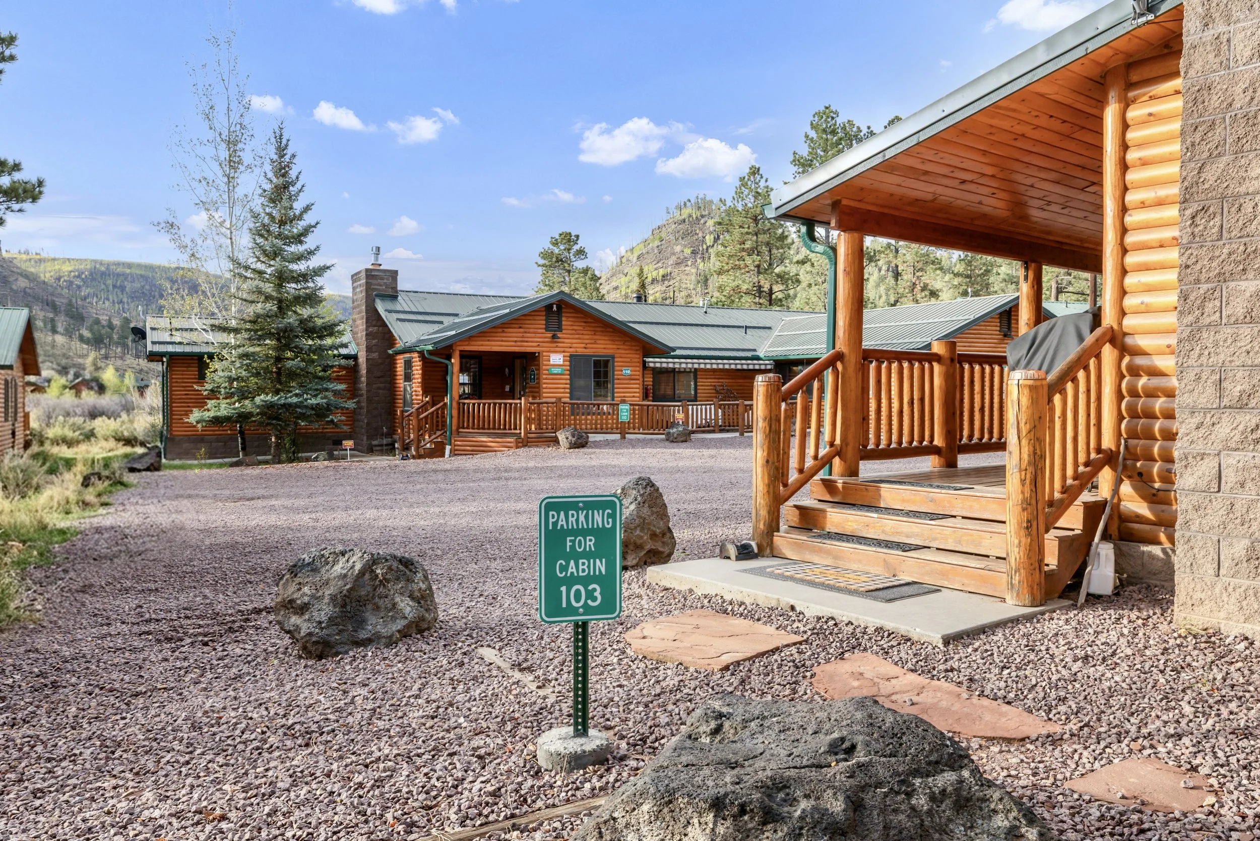 This real estate photography showcases charming log cabins with porches and mountain views in Greer, AZ, providing a cozy retreat surrounded by nature.